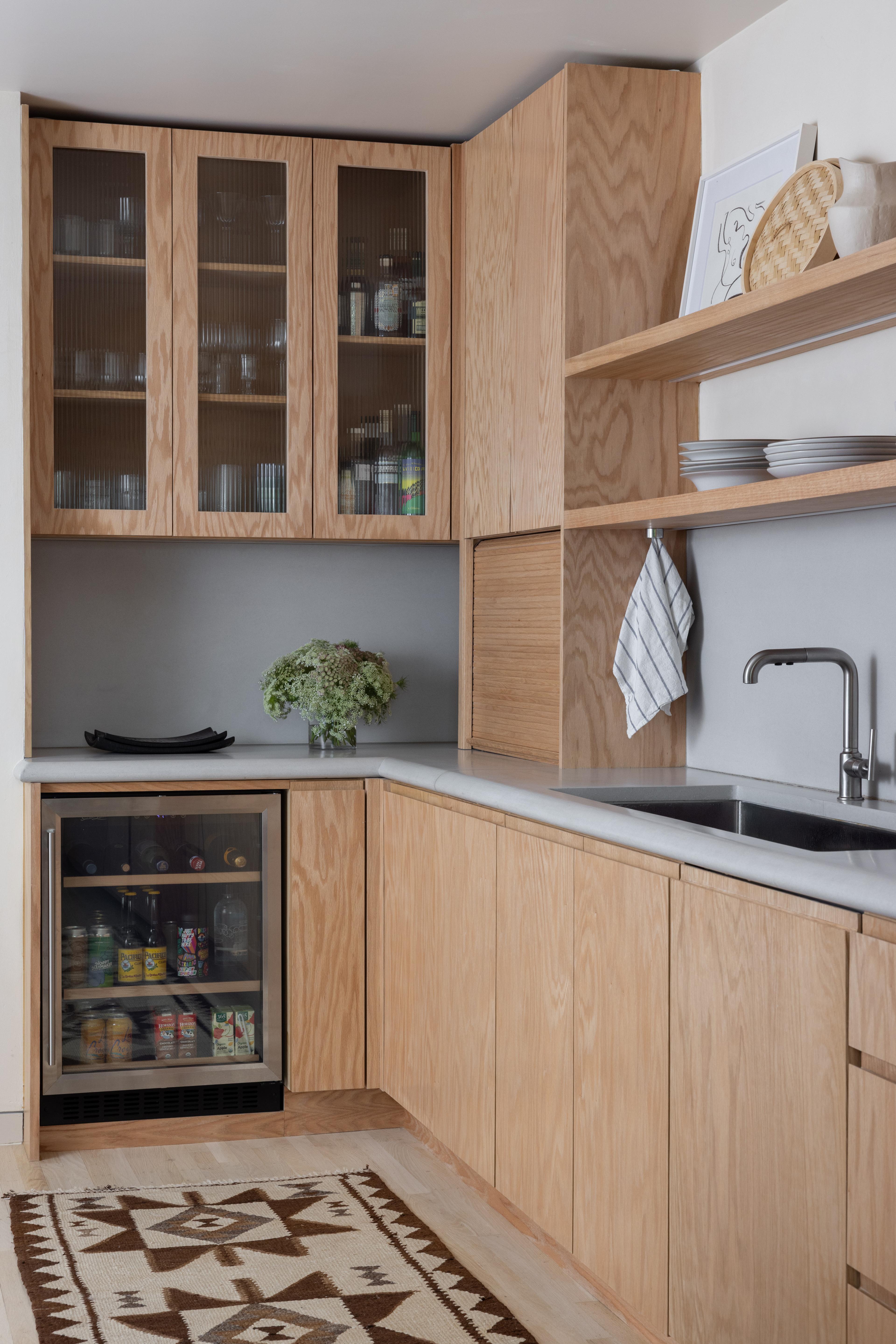 Parnassus Heights kitchen after the renovation, with red oak glass-front cabinets, a beverage fridge, and open shelving, designed by Studio VAE