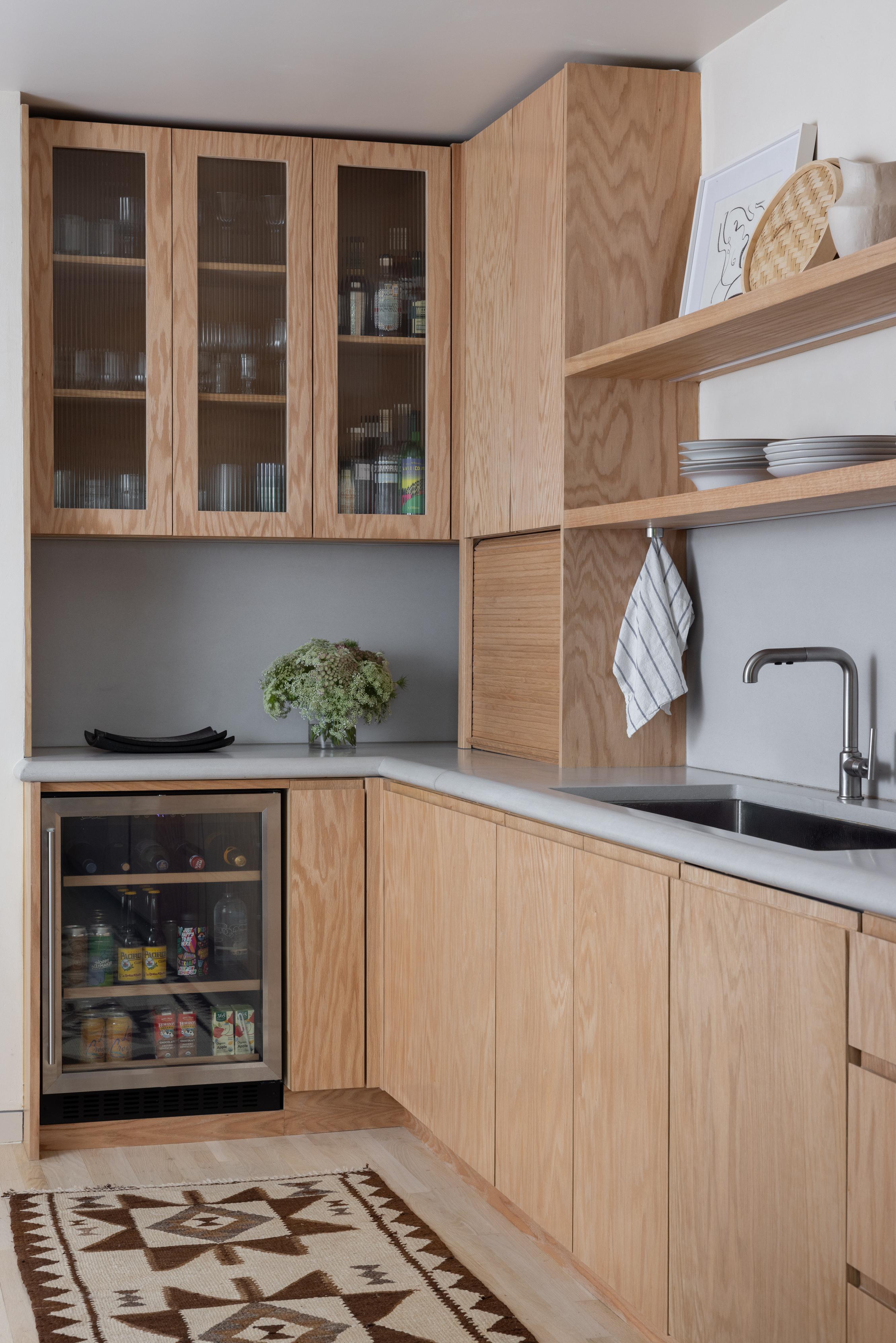 Parnassus Heights kitchen after the renovation, with red oak glass-front cabinets, a beverage fridge, and open shelving, designed by Studio VAE