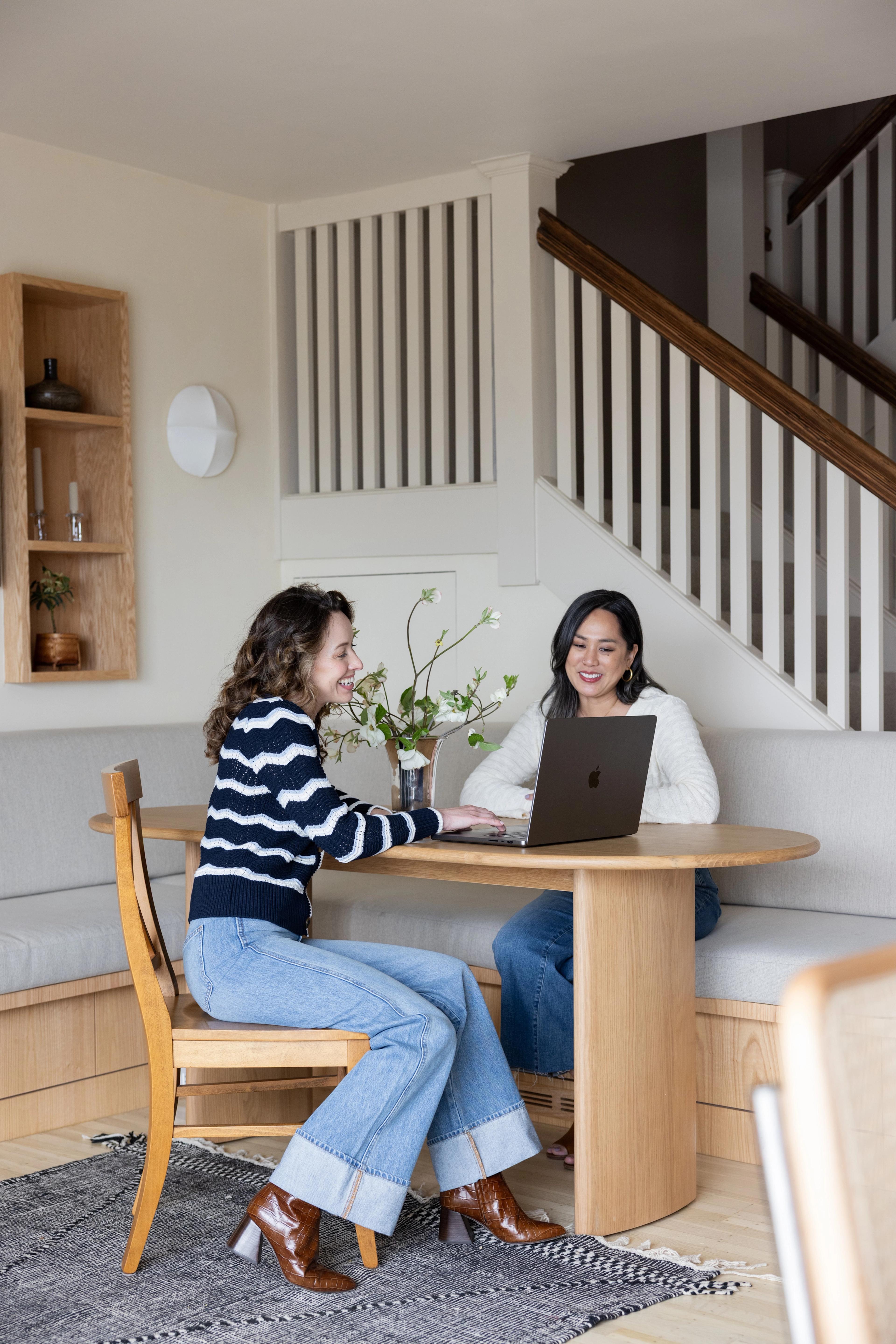 Studio VAE designers Veronica Jurist and Aggie Revane working together at a round white oak table in a client's home