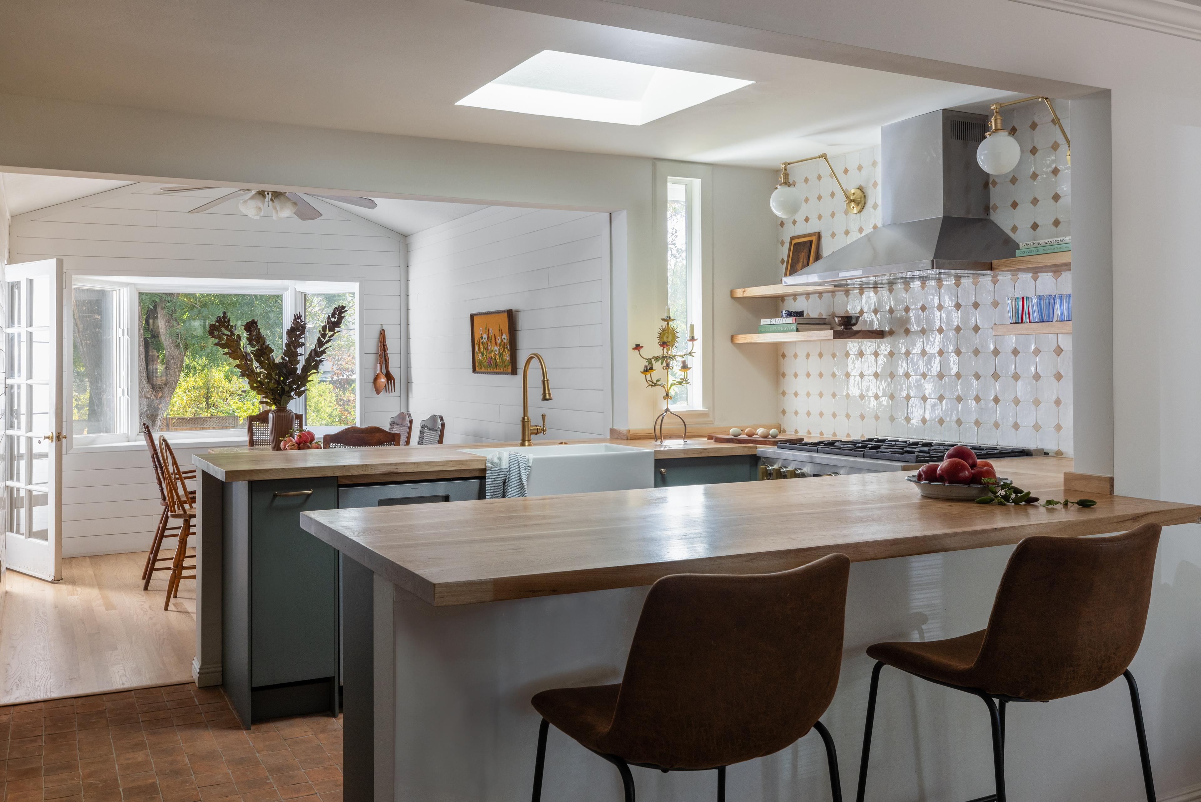 Kitchen with butcher block peninsula, leather counter stools, sage green cabinets, and zellige diamond tile backsplash in Carmichael home designed by Studio VAE, San Francisco interior designer.