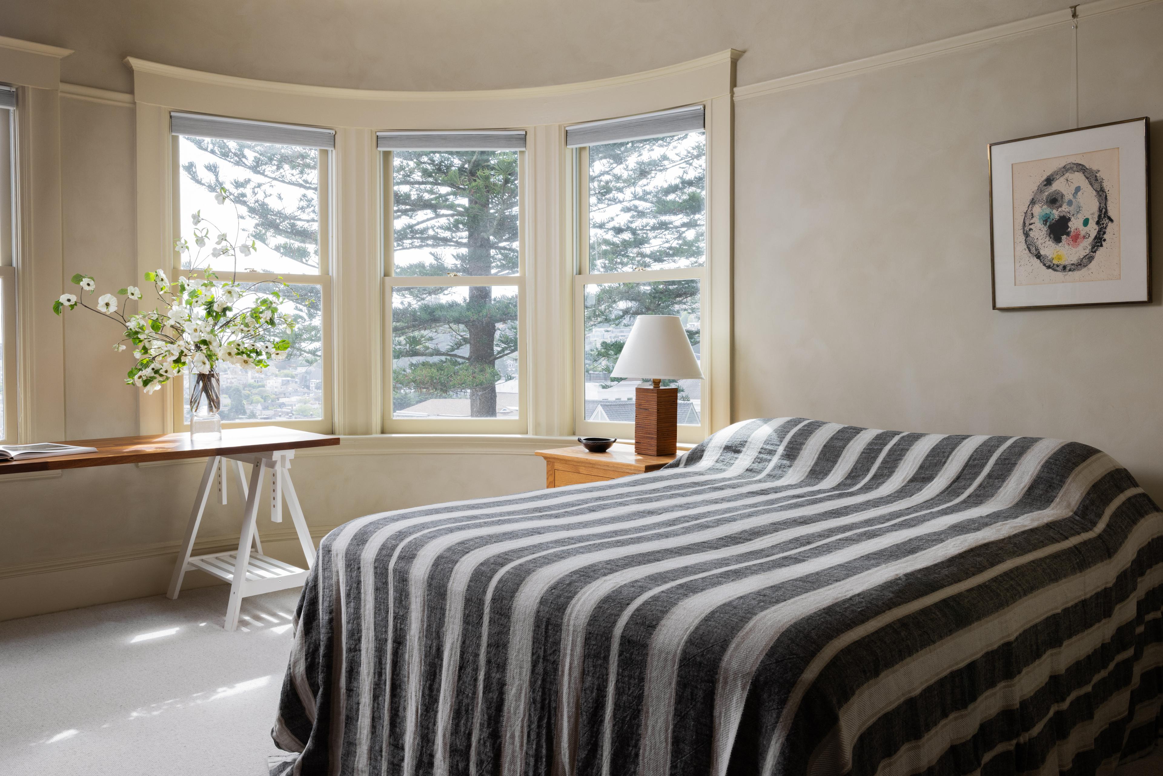Guest bedroom in a Parnassus Heights home, with paper pendant light, lime washed walls and a striped bedspread