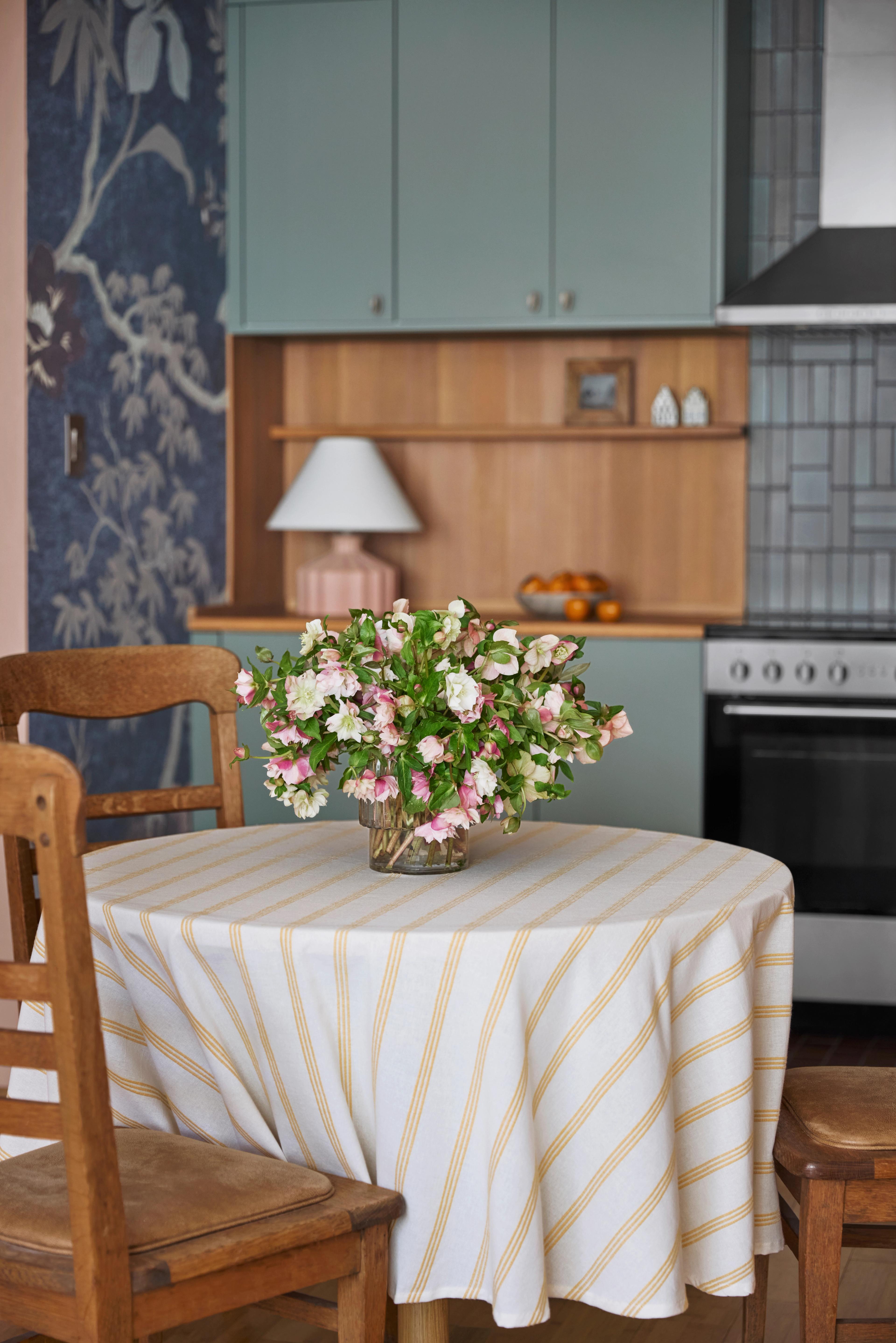 Dining room with round table, yellow striped tablecloth, and chinoiserie-inspired wallpaper in Outer Sunset home designed by Studio VAE, San Francisco interior designer.