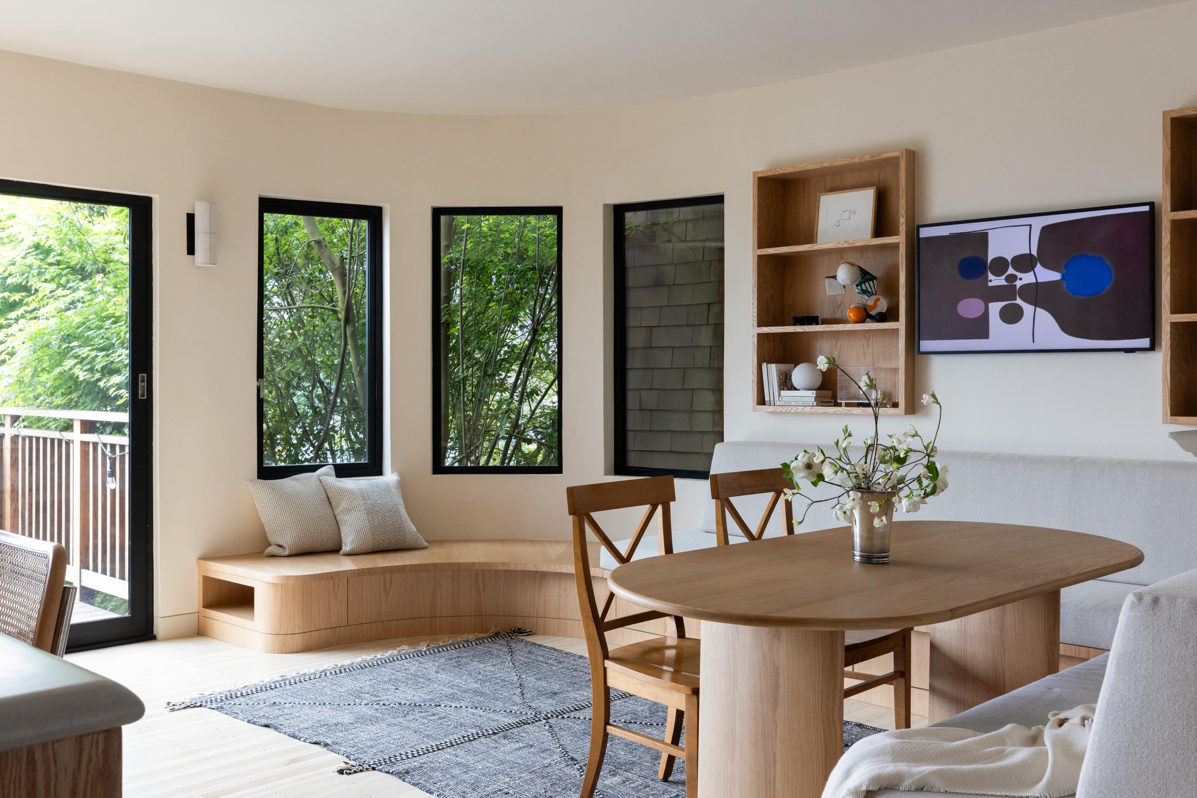 Parnassus Heights dining area with a curved red oak window bench, an oval oak pedestal table, and built-in shelving, designed by Studio VAE