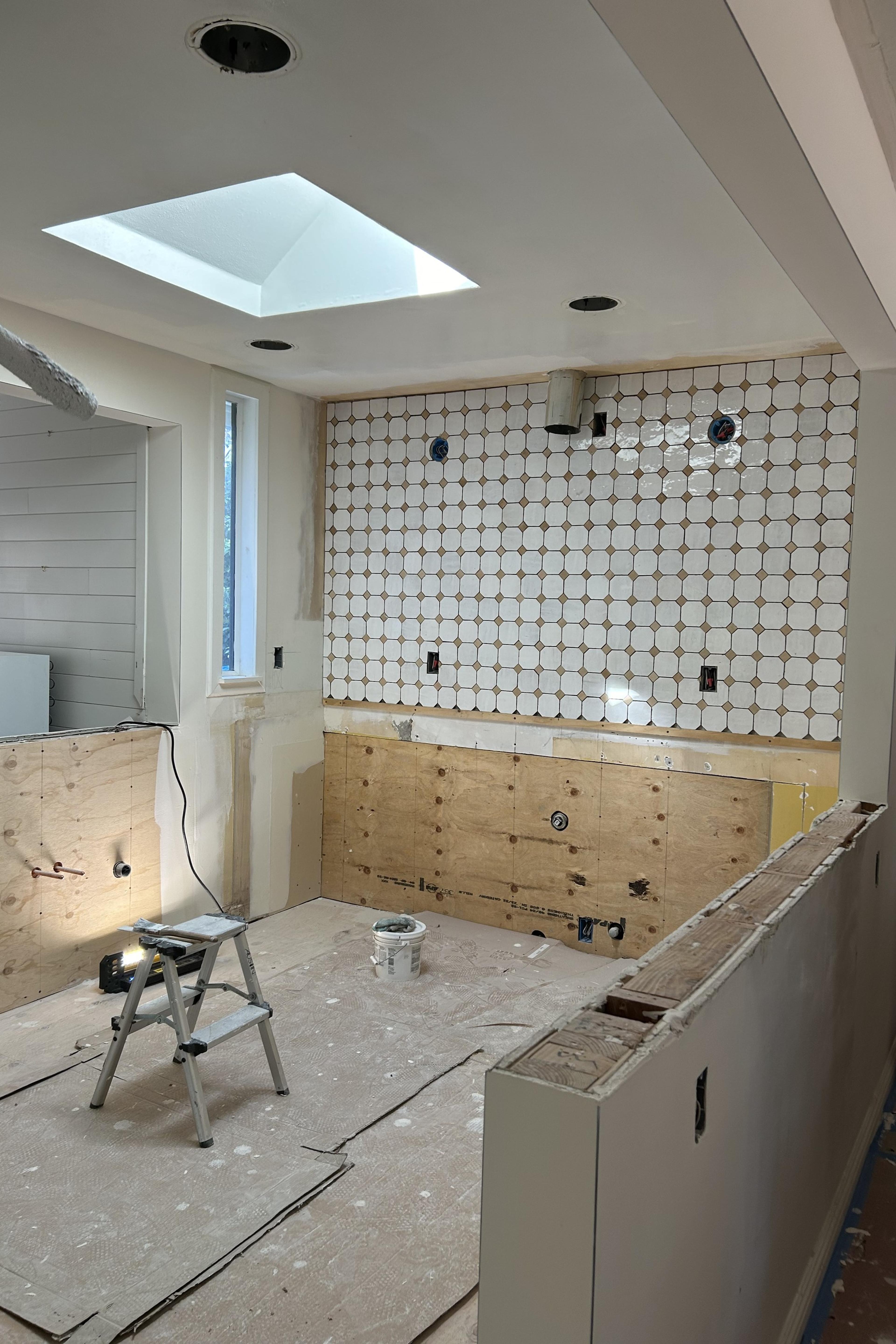Carmichael kitchen during construction, with the skylight in place, plumbing roughed in and tile going up on the back wall