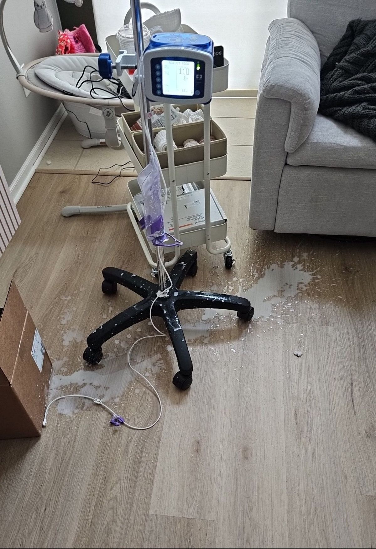 Feeding pump stand and supplies in a living room after formula spilled onto the floor.