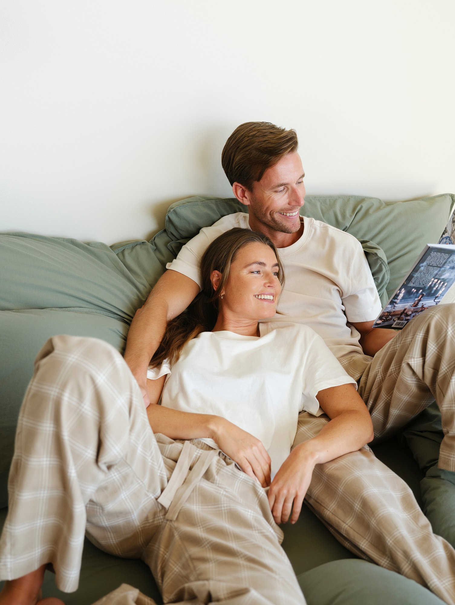 Par som slapper av i myke flanellpyjamasbukser i beige rutemønster – komfortable pysjbukser i flanell for dame og herre, perfekt til avslappende kvelder og helgemorgener.