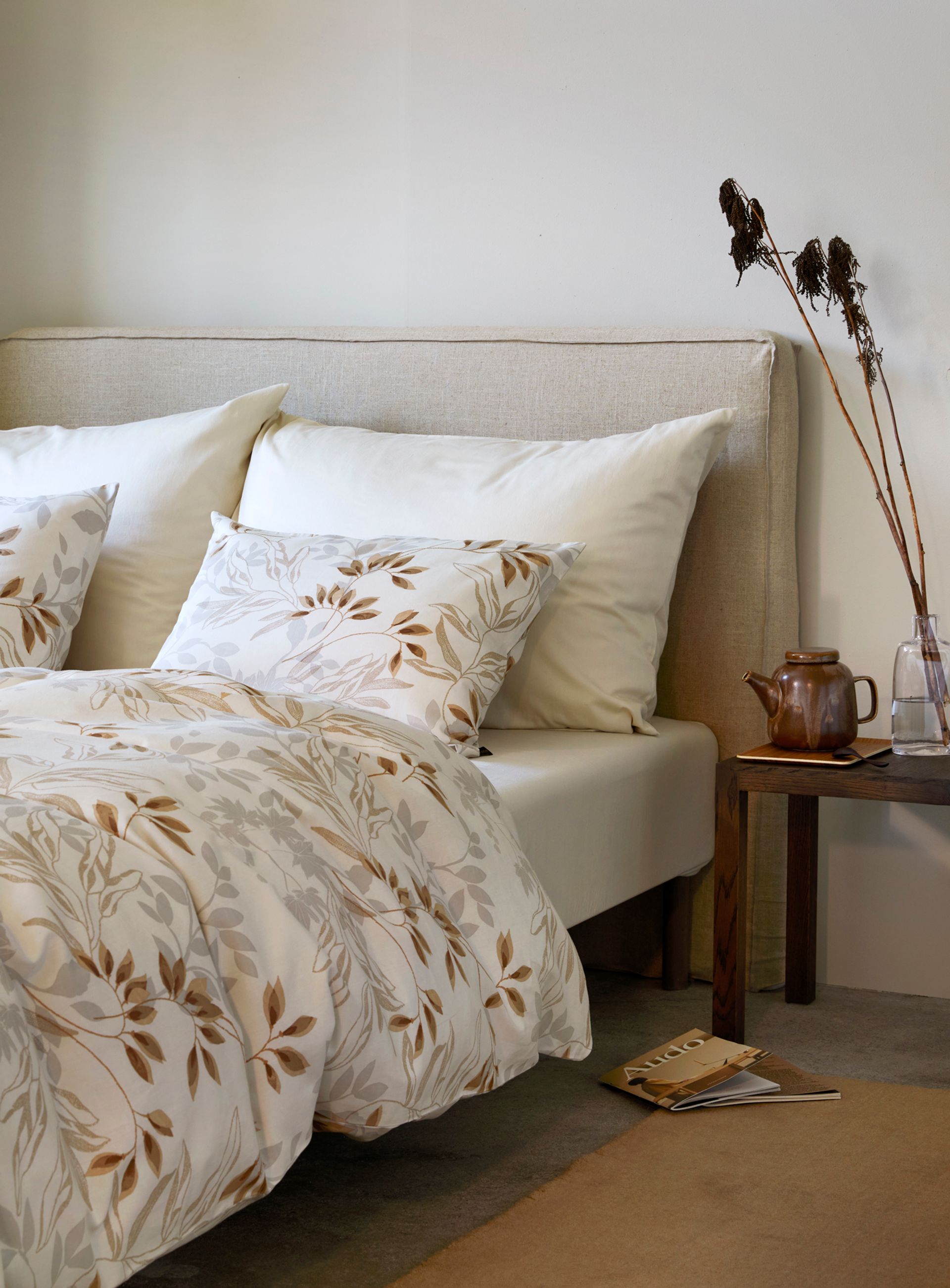 Nærbilde av oppredd seng med Høie Tor og Frøya sengesett i beige – en avslappet miks av smale striper og ensfarget bomull, som skaper en rolig og lun atmosfære på soverommet.