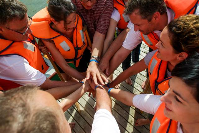 Team in Schwimmwesten klatscht zusammen