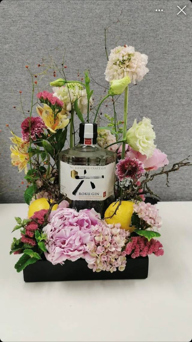 Gin-Flasche in festlichem Blumenarrangement