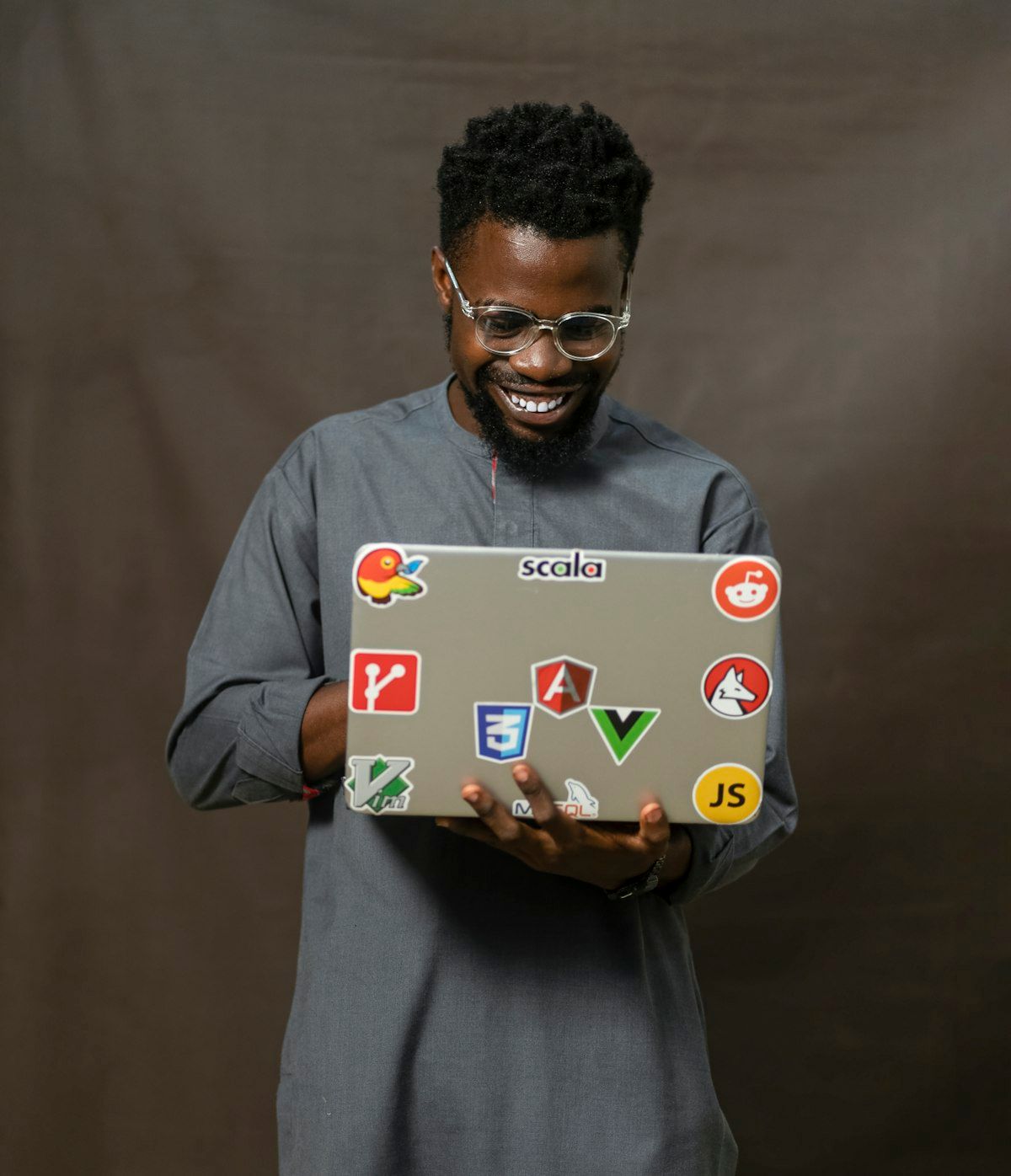 Developer holding a laptop covered in tech stickers ready for software development