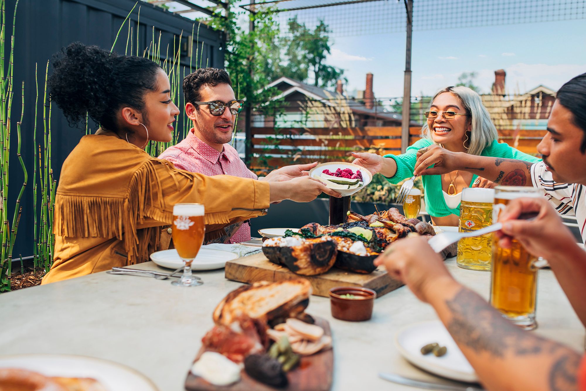 A group of people enjoying a meal together outdoors at a table with food and drinks.