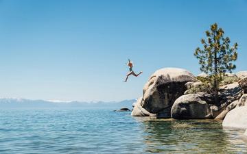 Girl jumping off rocks to swim in Lake Tahoe