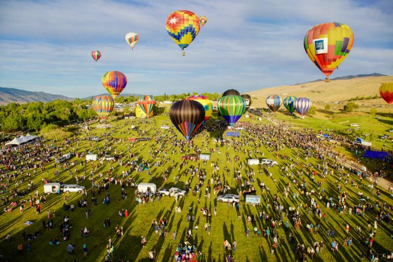 Hot air balloons in the sky over a field of spectators