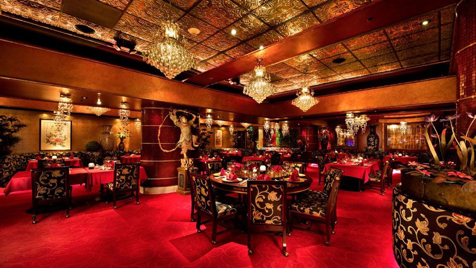 a luxurious dining room with red carpet, chandeliers, and ornate ceiling