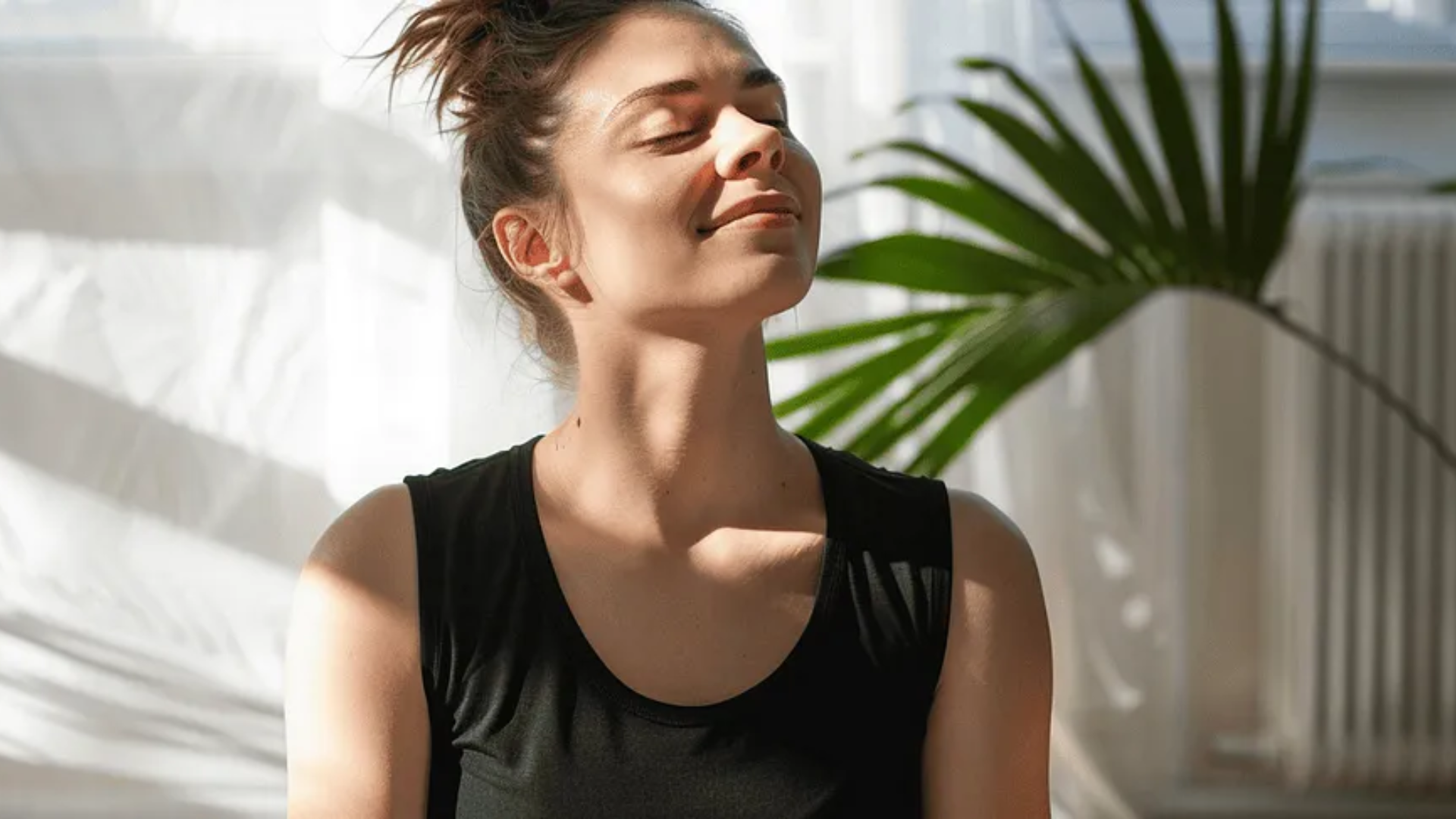 Image of a woman sitting indoors with her eyes closed looking up.