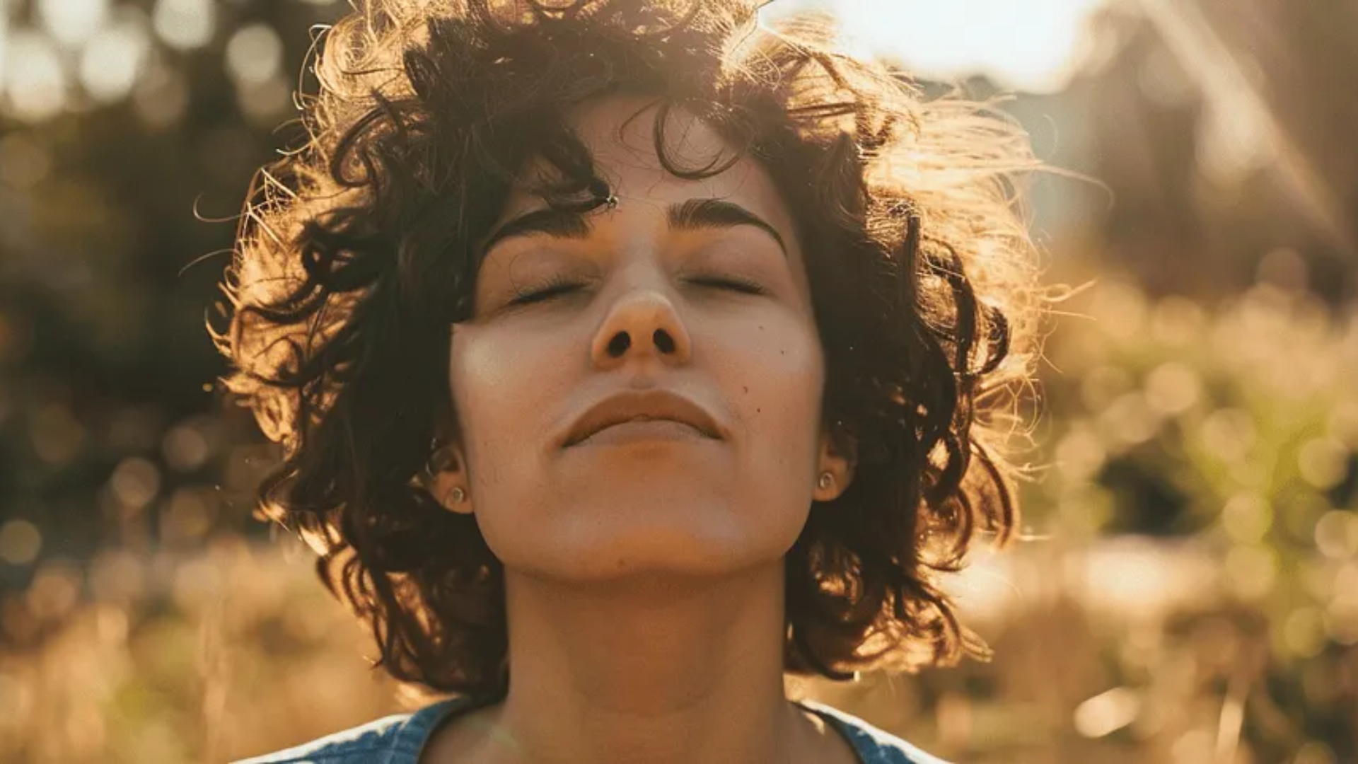 A Woman face with curly hair sitting outside looking up