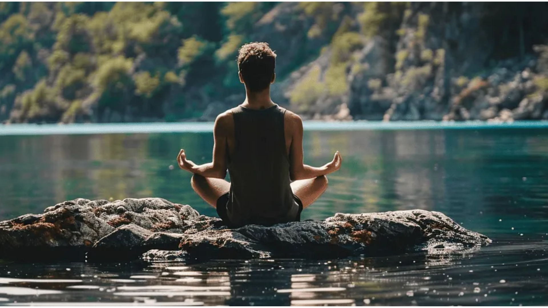 A man with his back turned sitting on a rock in a body of water in a mediation position