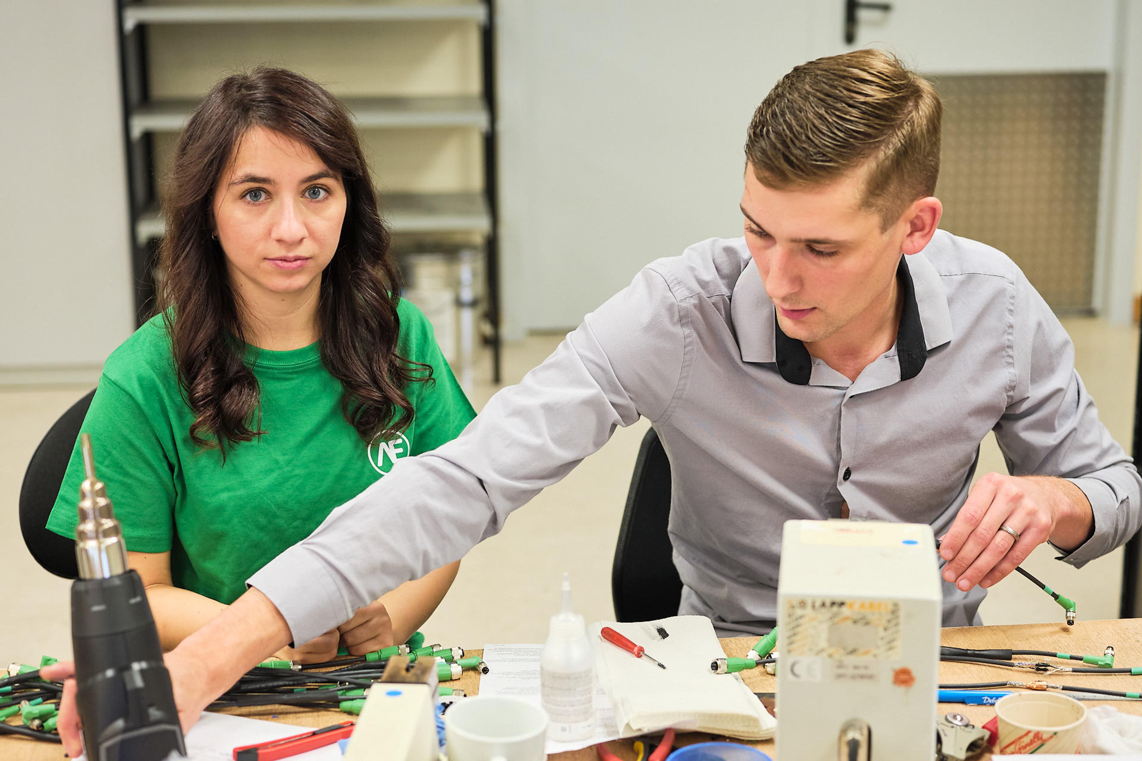 a man and a woman are sitting at a table working on a project .