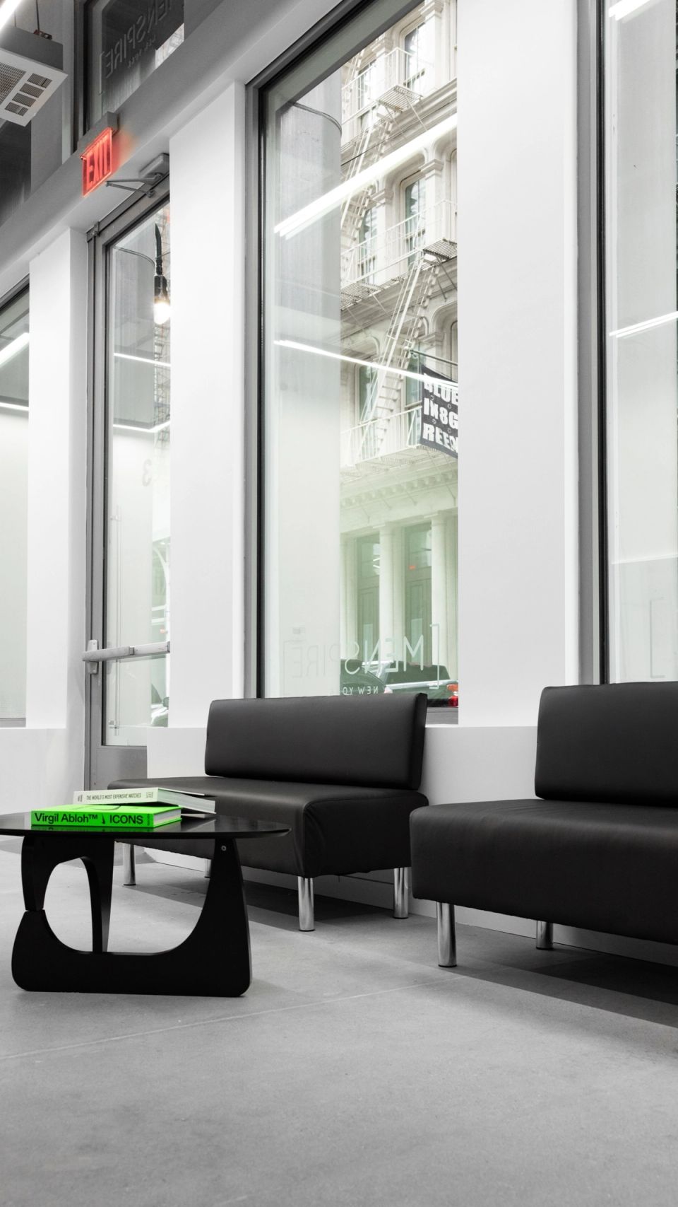 Black sofas by the tall front windows of MENSPIRE New York, with Greene Street outside