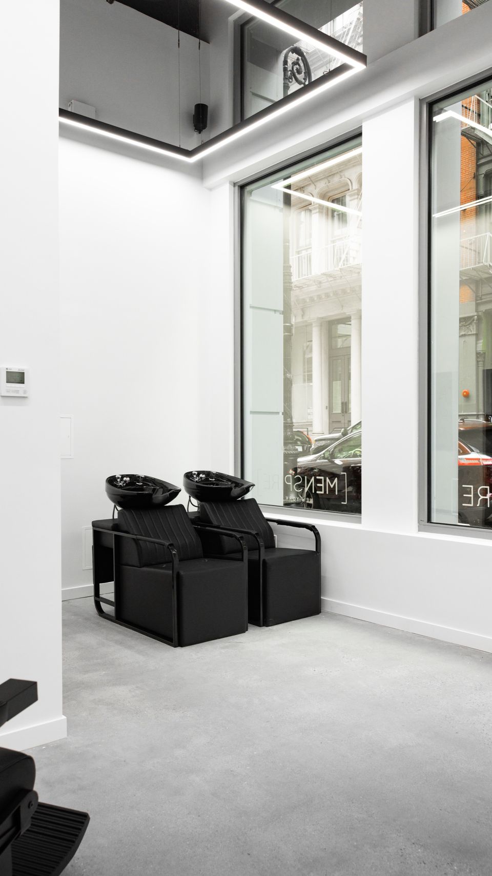 Two black shampoo basins beside the tall windows at MENSPIRE New York