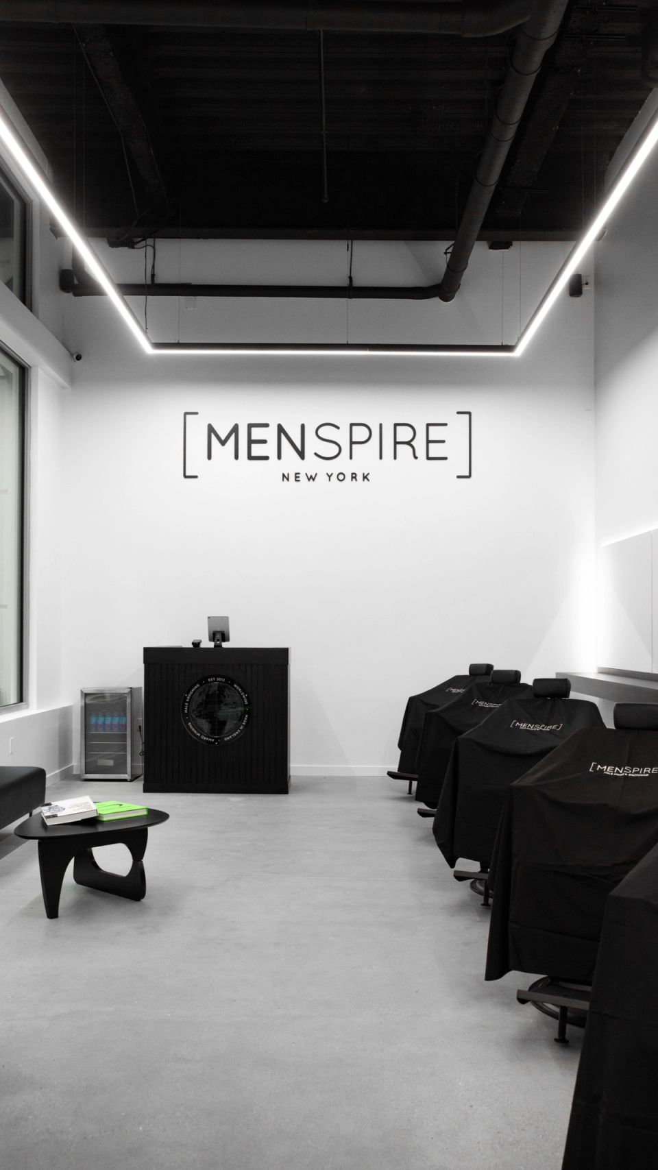 Inside MENSPIRE New York on Greene Street, the MENSPIRE logo on a white wall above the front desk
