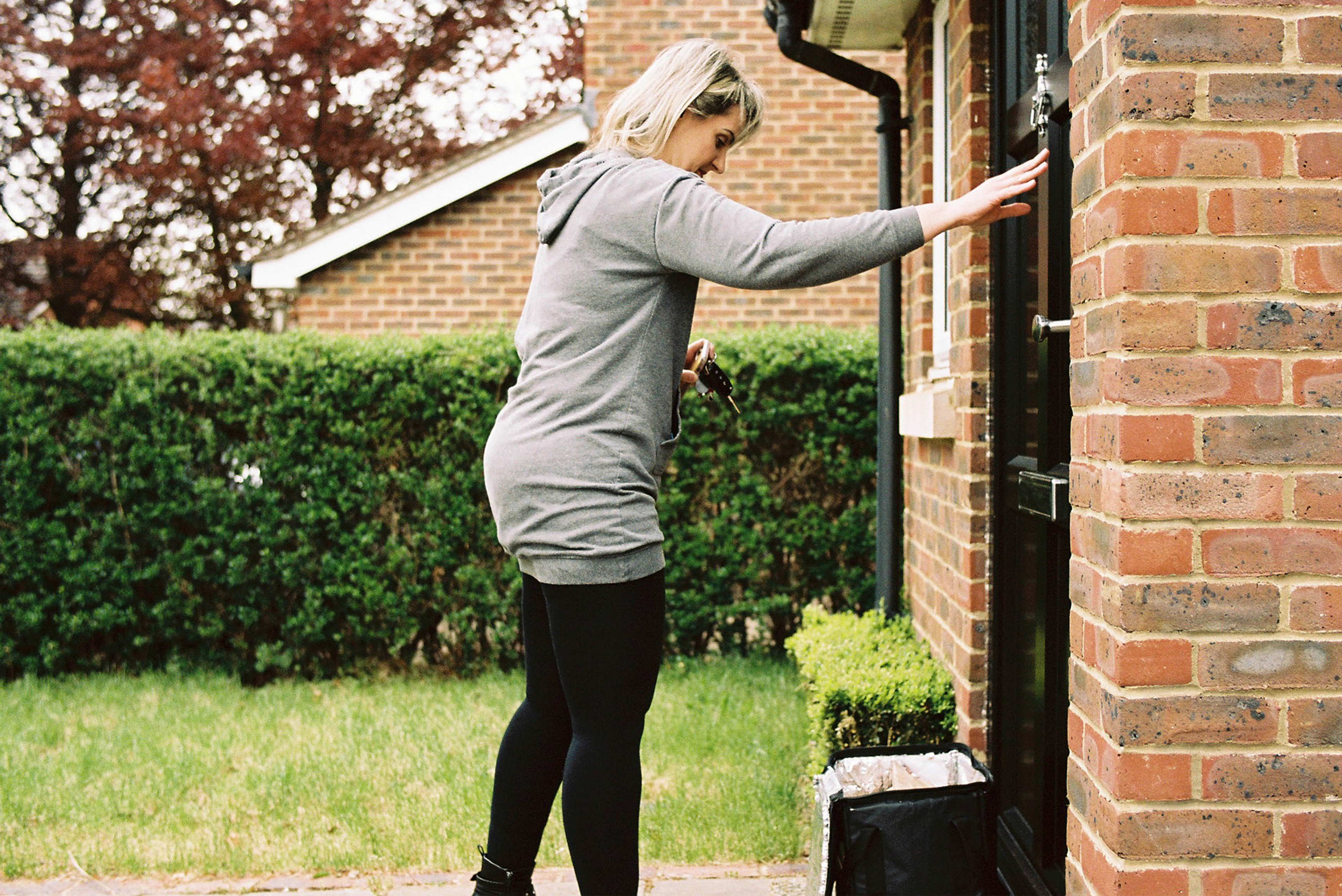 courier delivery woman ringing doorbell with delivery on doorstop