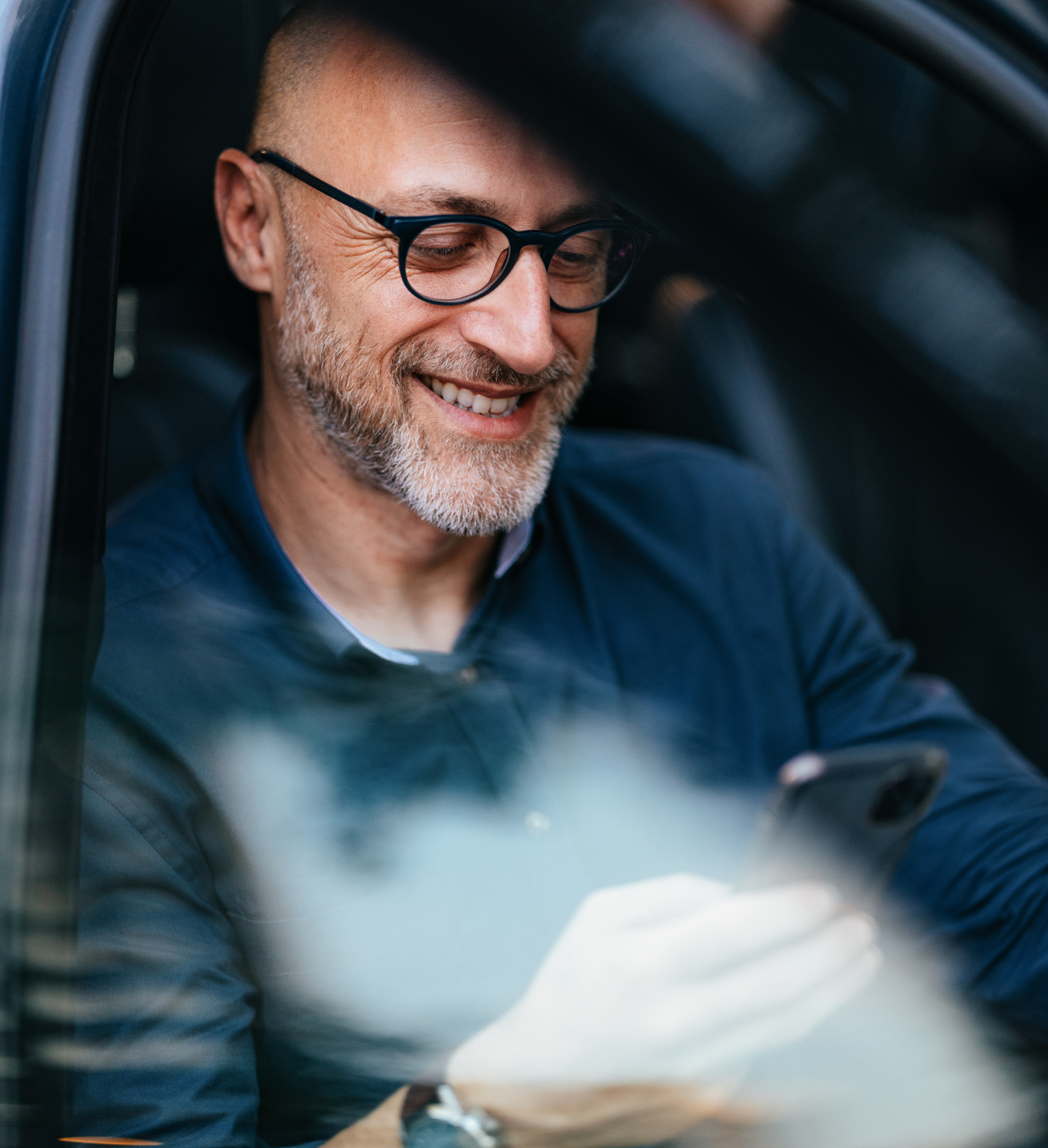 Smiling Zego taxi insurance customer looking at his policy on this phone