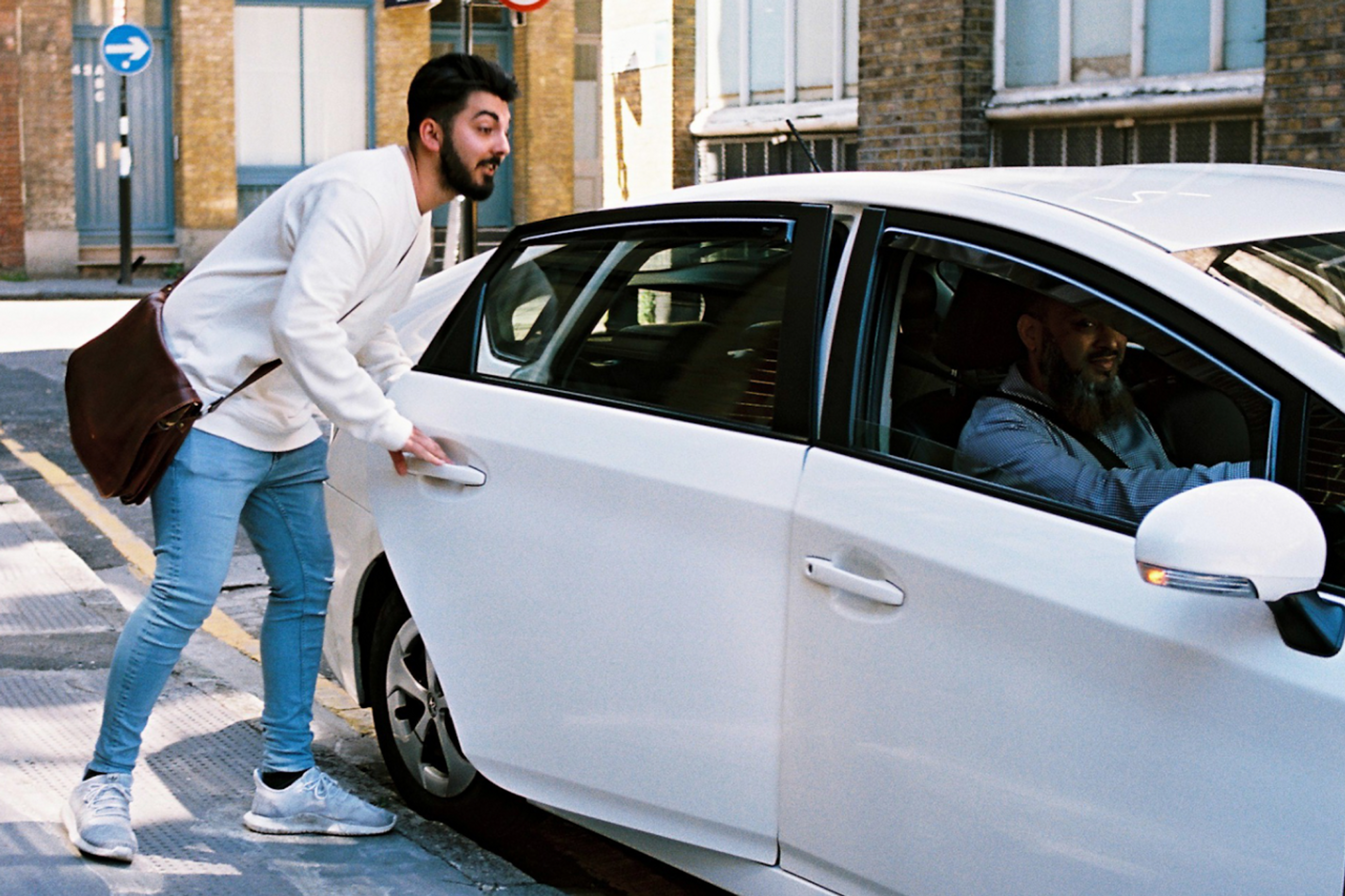 a customer getting into a white Uber car
