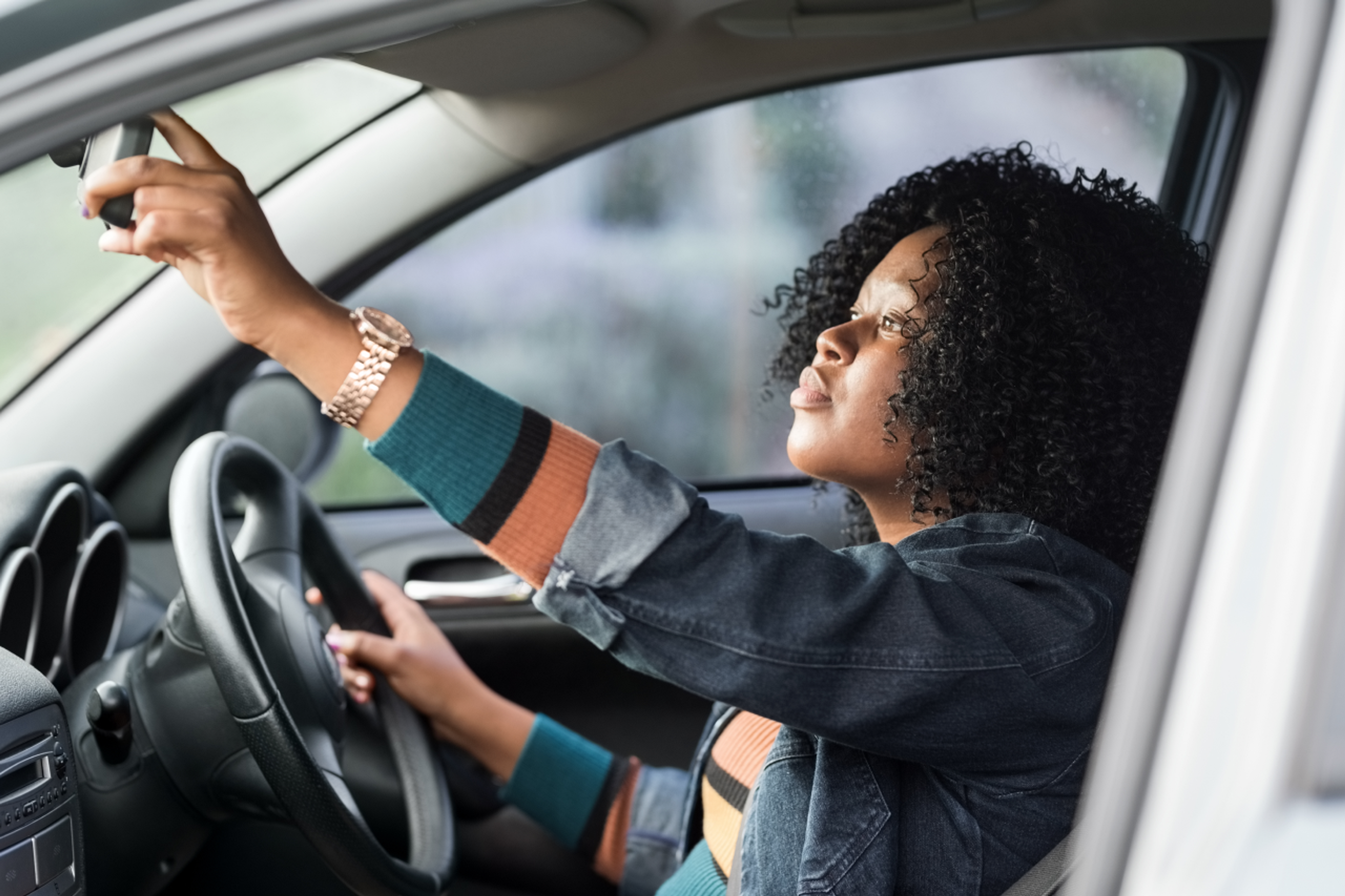 woman in car adjusting rearview mirror