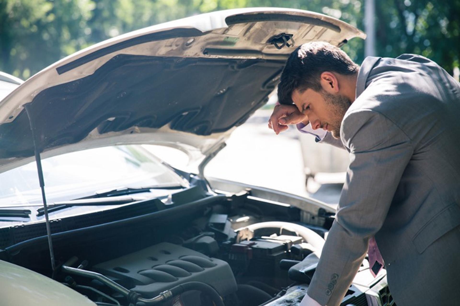 man looking at private hire car engine in suit