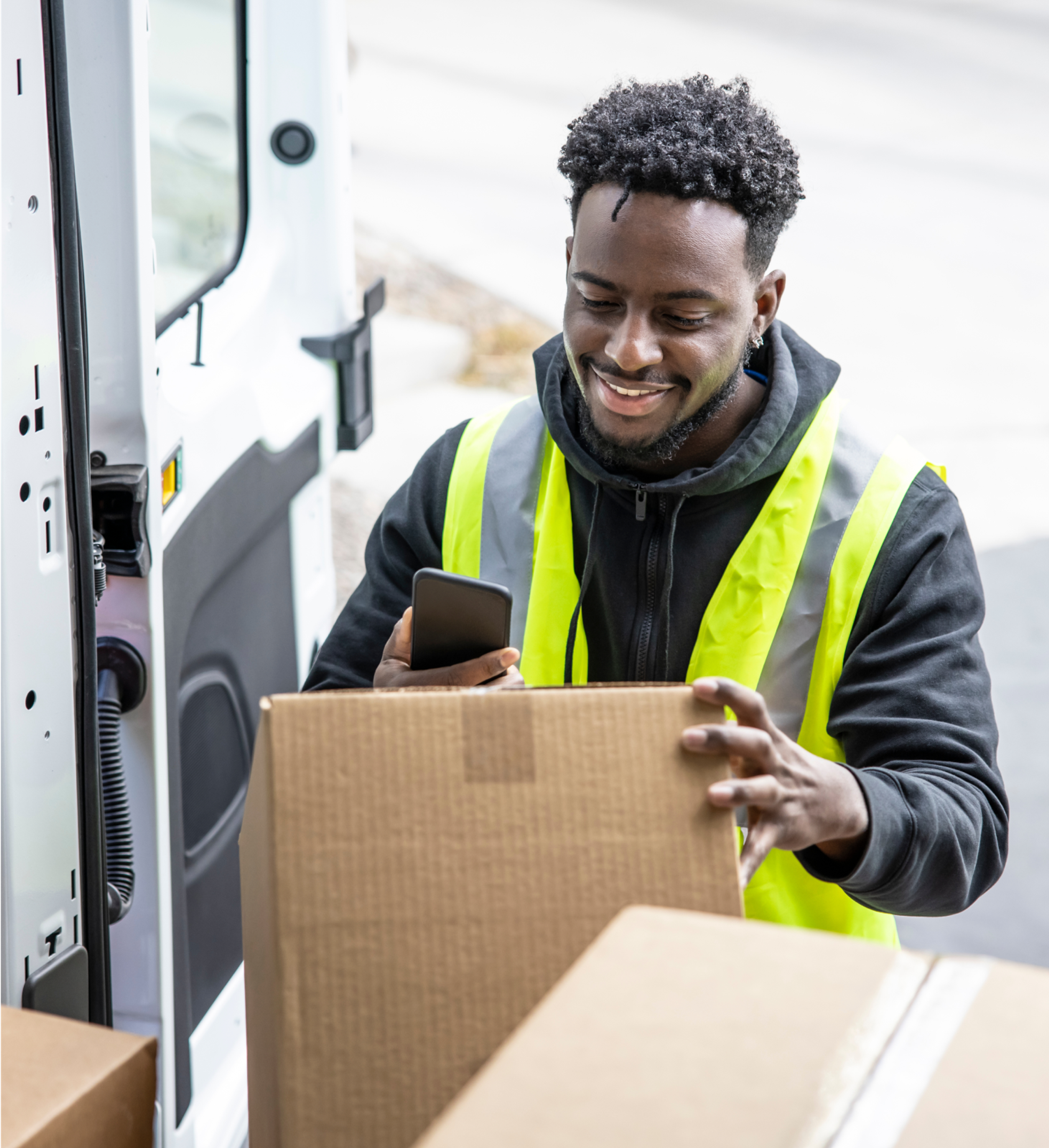 Smiling Zego courier van driver scanning a parcel in the back of his van