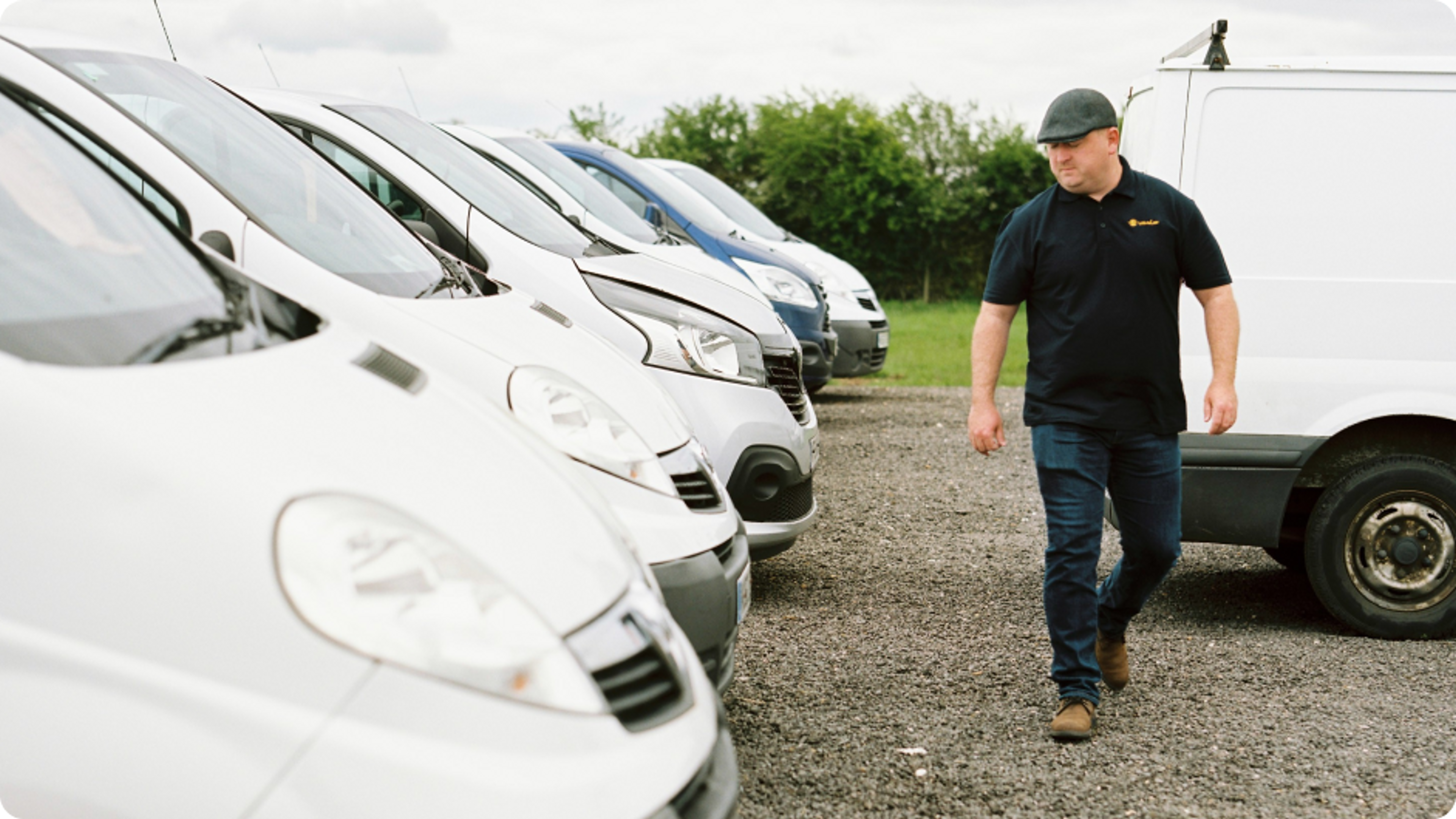 Tradesman walking past his fleet of work vans insured by Zego