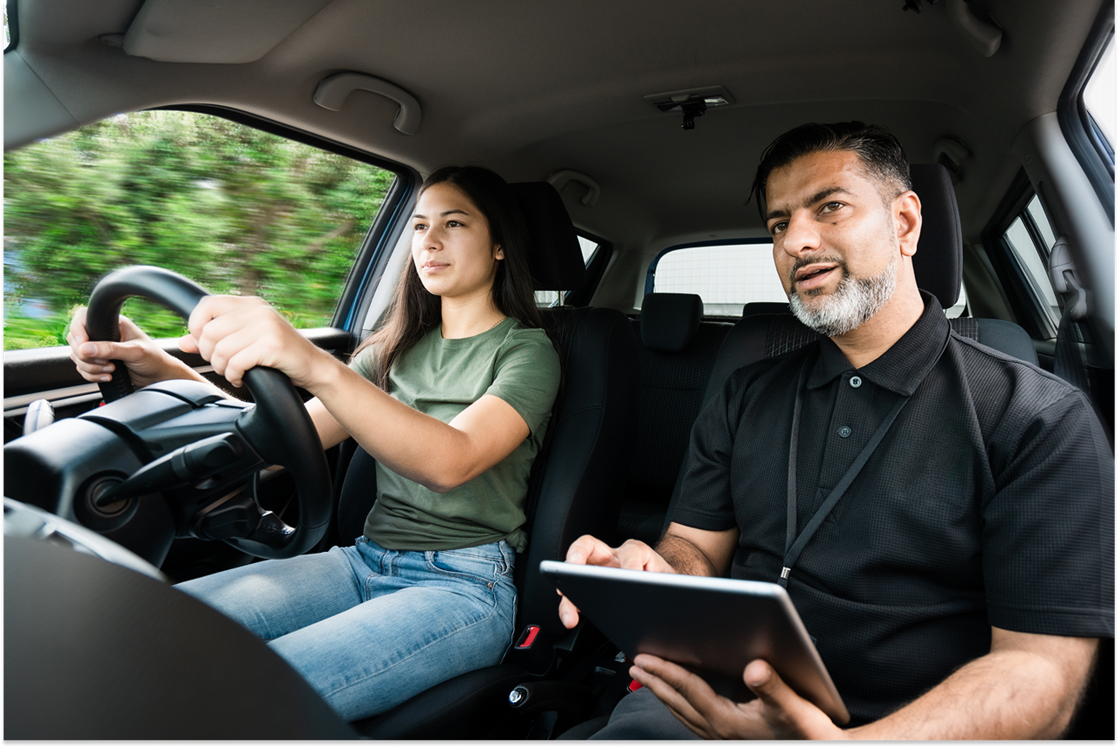 Young female driver driving during a lesson with a driving instructor