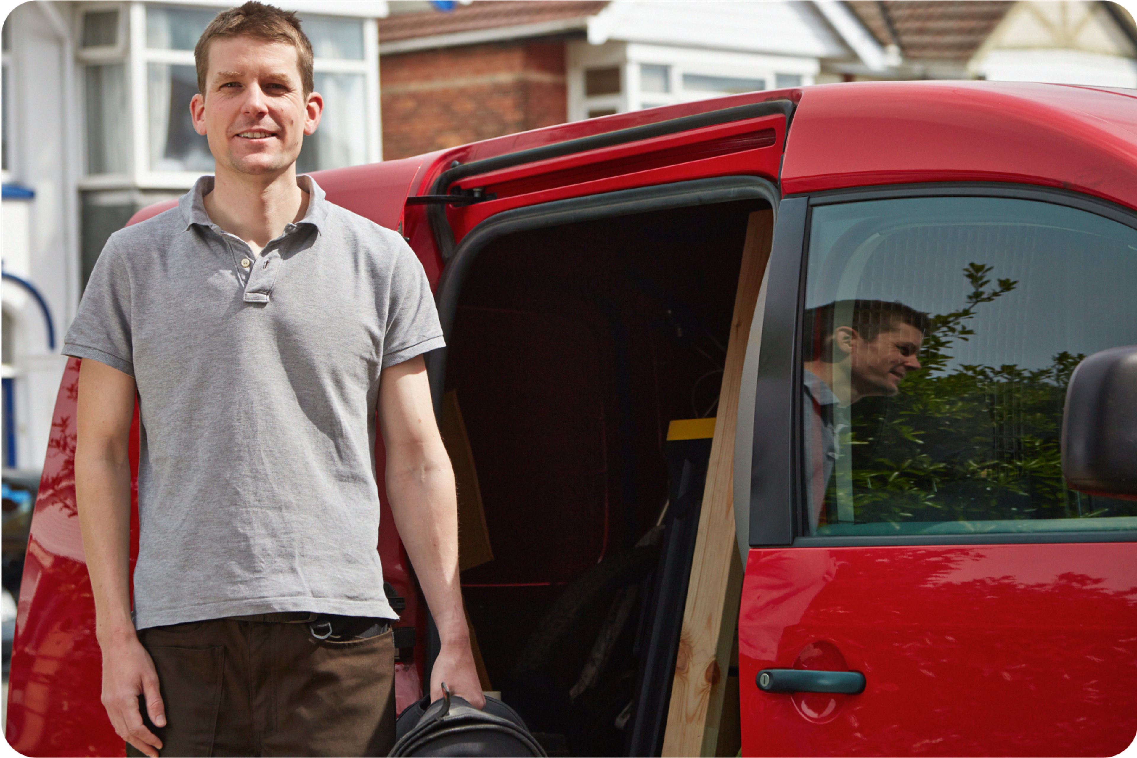 Smiling Zego business van customer standing next to his red van