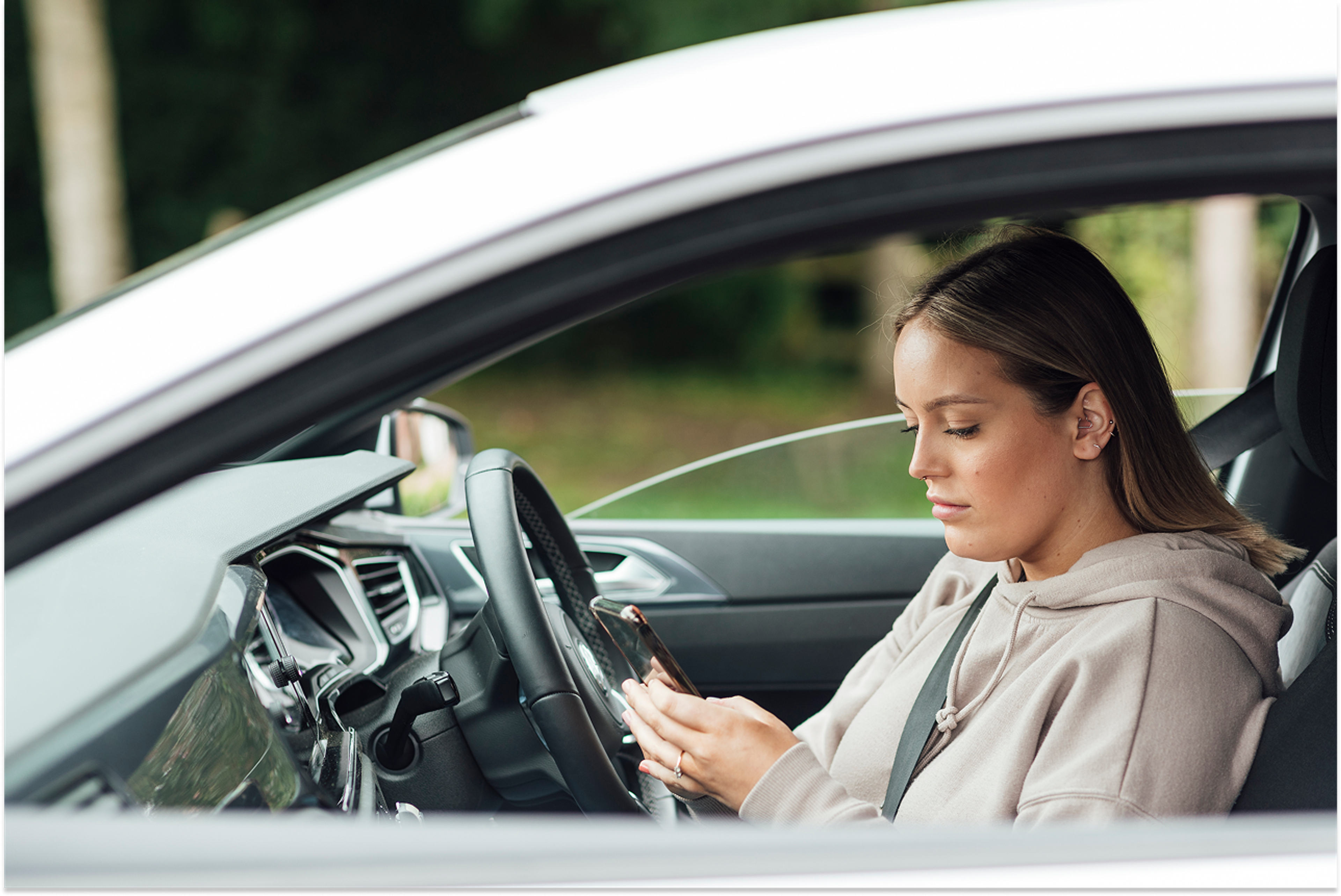 Female driver in a parked car looking at her phone
