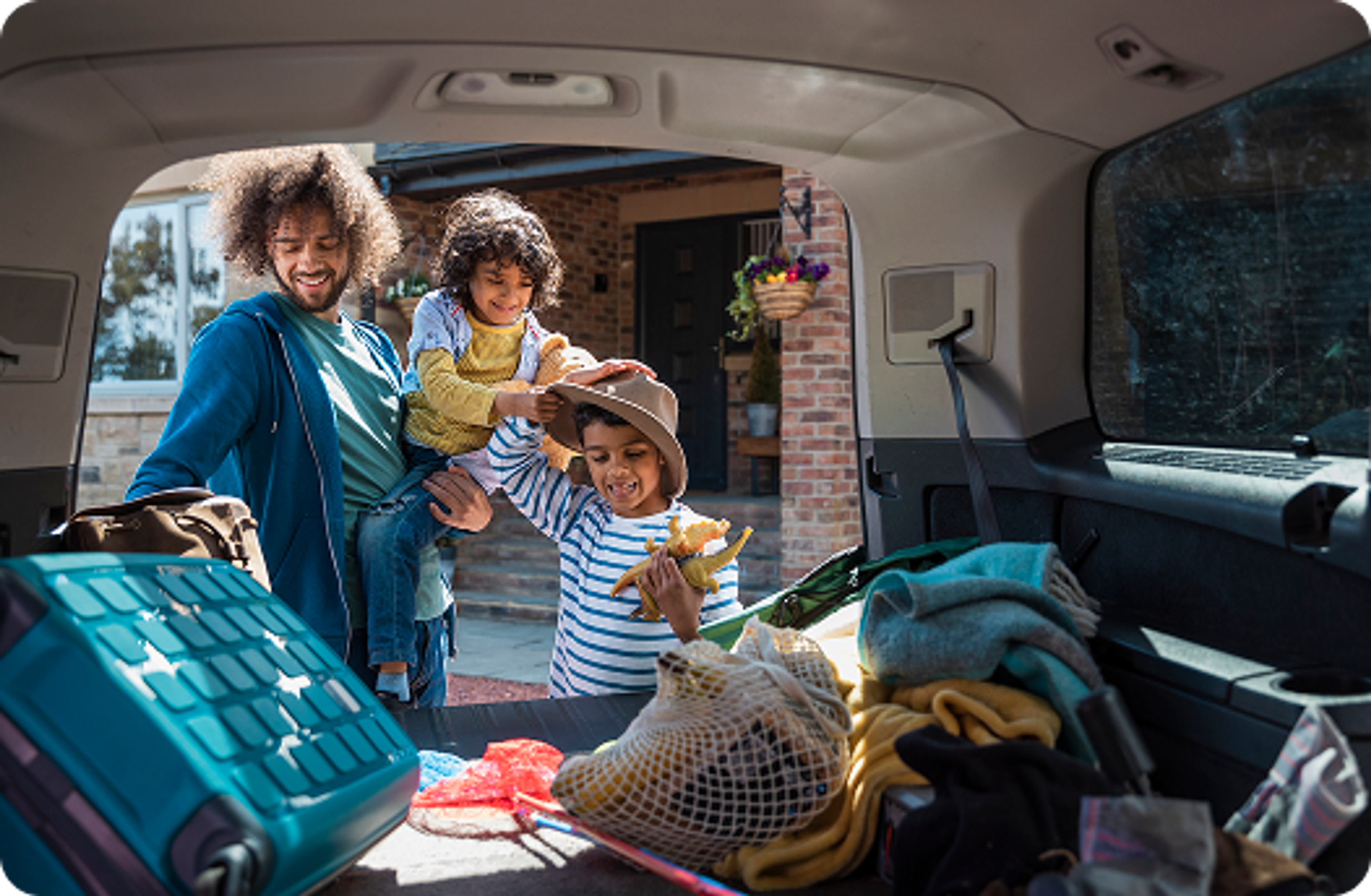 Young family packing luggage in car boot