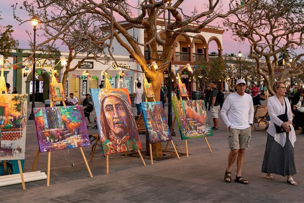 Visitors browsing paintings displayed on easels at sunset during the San José del Cabo Art Wal