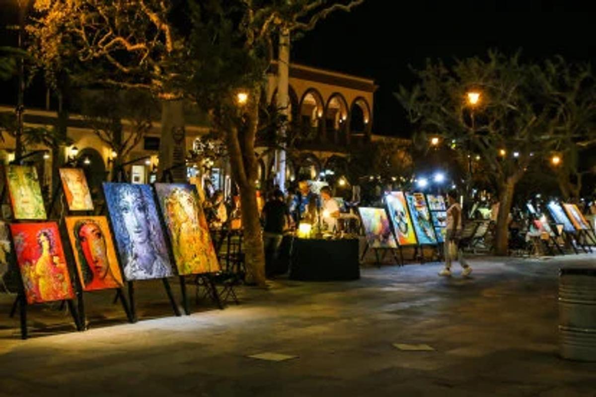 Art vendor displaying landscape paintings and local artwork at the San José del Cabo Art Walk plaza
