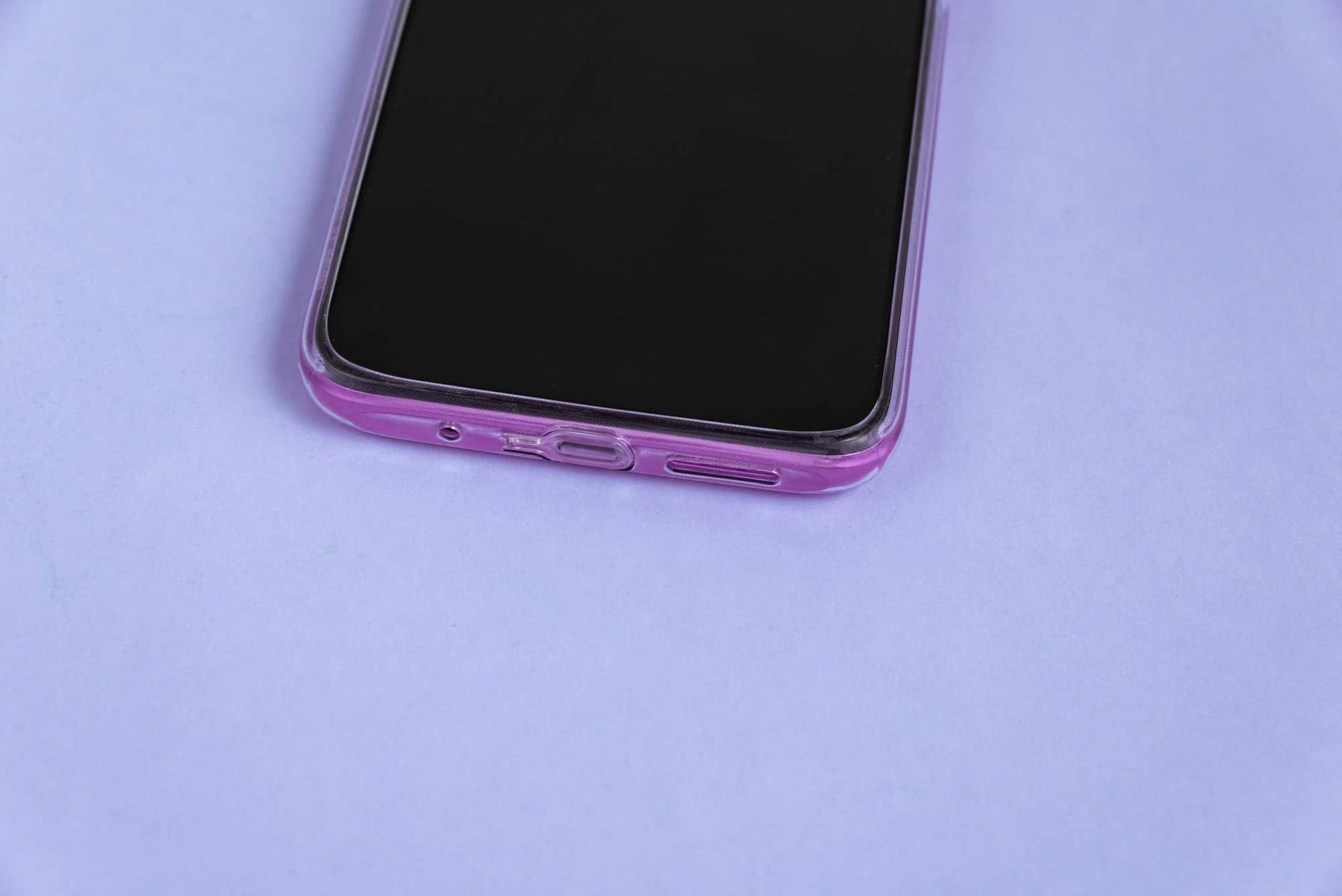Primo piano di uno smartphone con cover rosa su una superficie color lavanda.