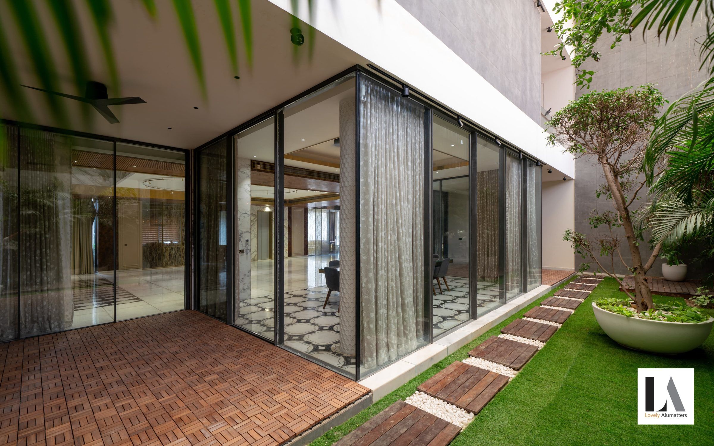 Corner of full-height sliding glass doors opening onto a timber deck and garden