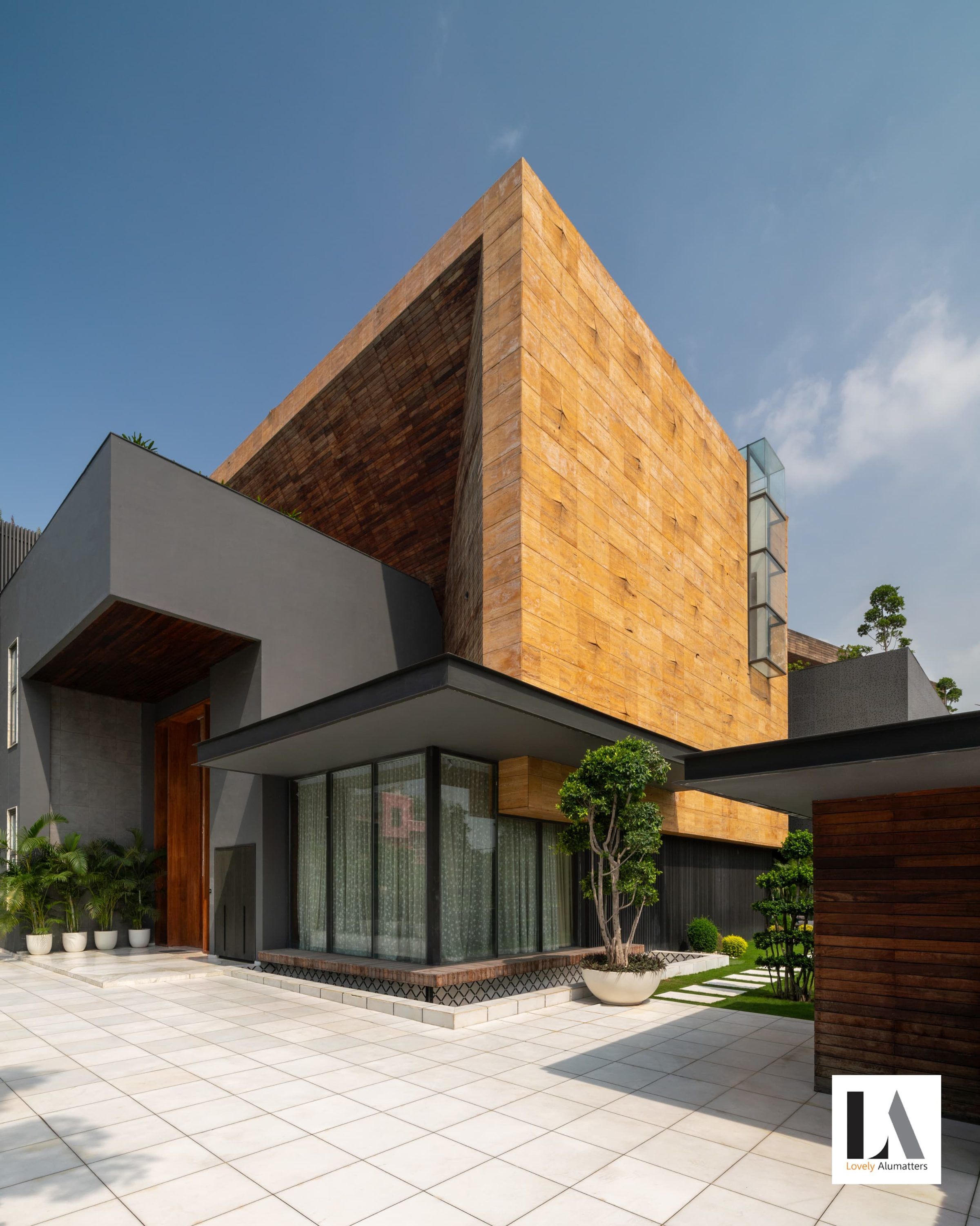 Residence with a sculptural stone-clad volume above a glazed ground floor, seen from the courtyard