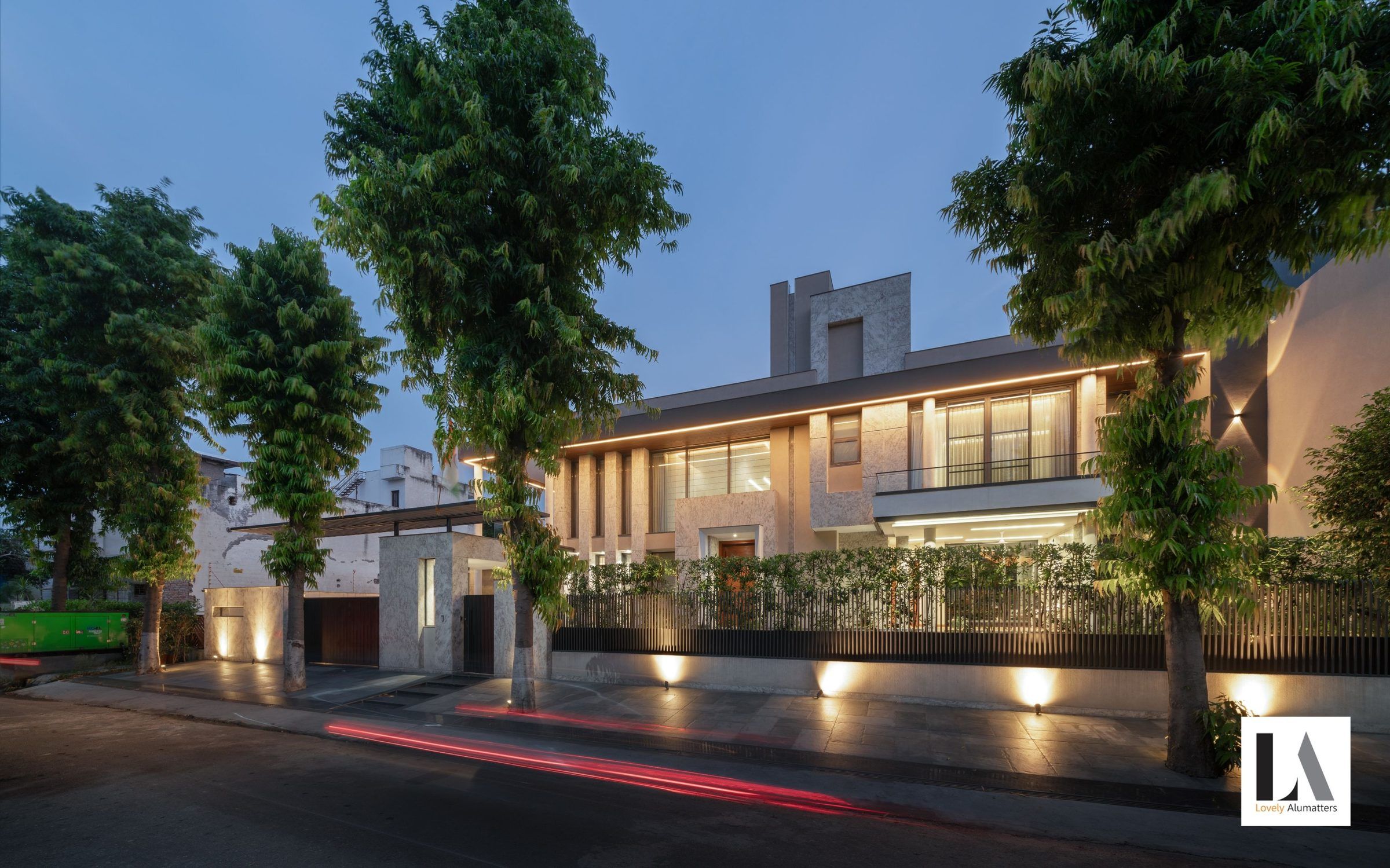 Stone villa at dusk with illuminated glazing along the street