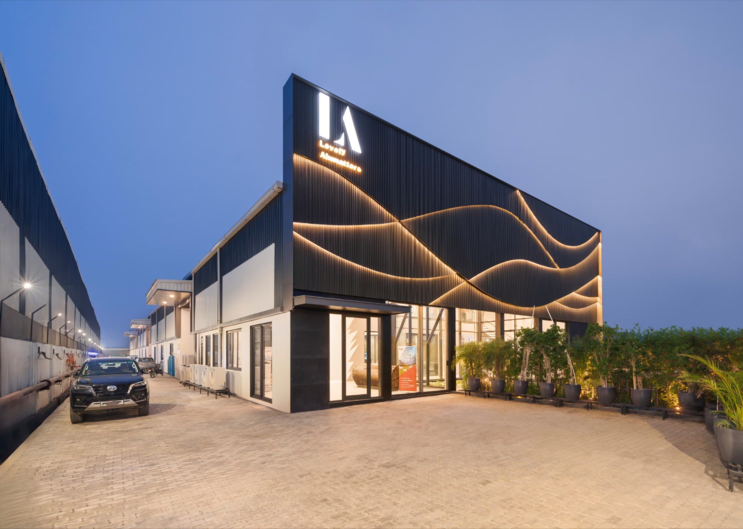 The ALUVIA facility at dusk, with illuminated wave detailing on the façade