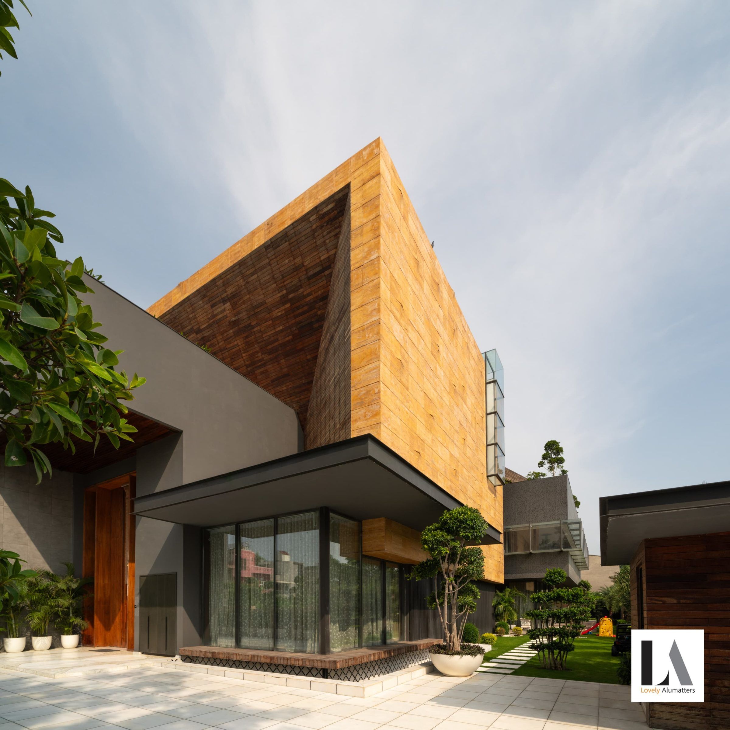 Stone and timber façade rising over a corner of floor-to-ceiling glazing