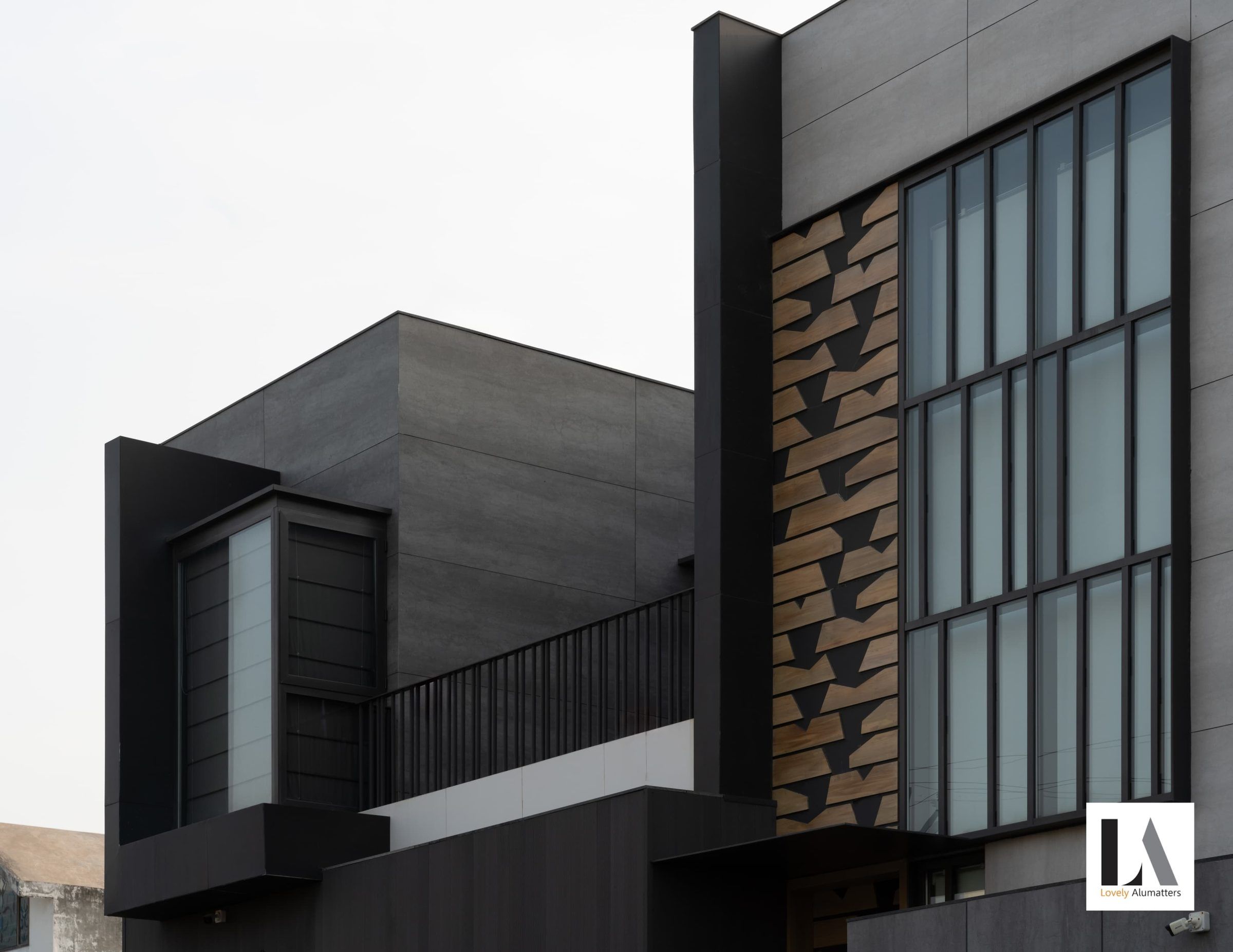Dark corner volume with tall gridded glazing beside a textured stone panel