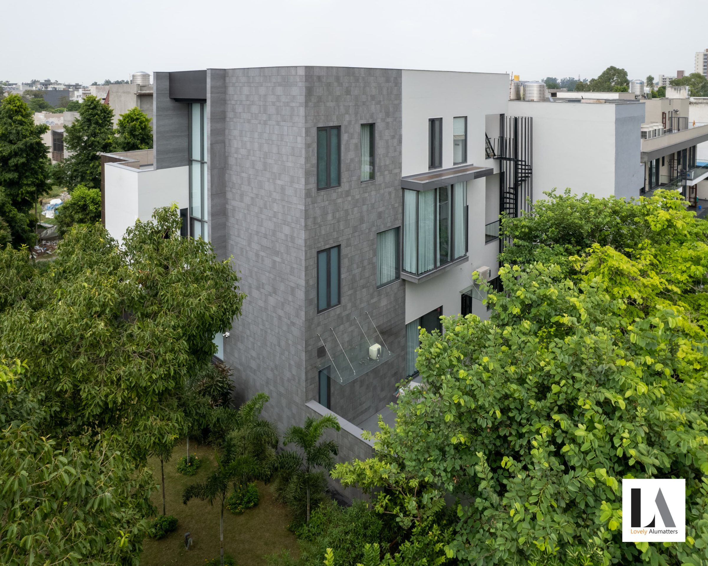 Side elevation with stacked windows and a glazed bay, surrounded by trees