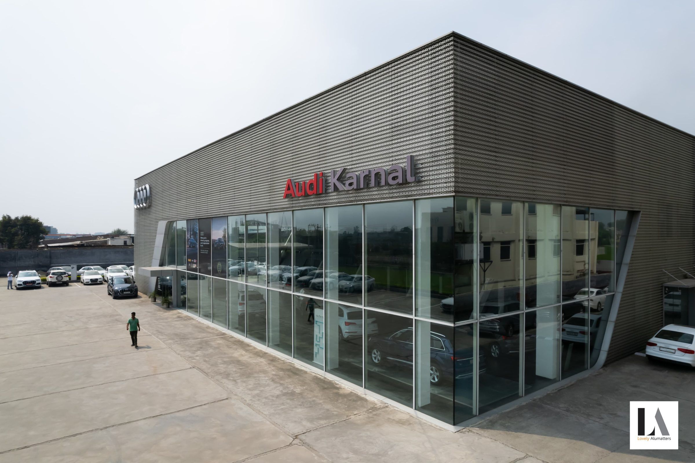 Automotive showroom corner with full-height glazing under a ribbed metal façade