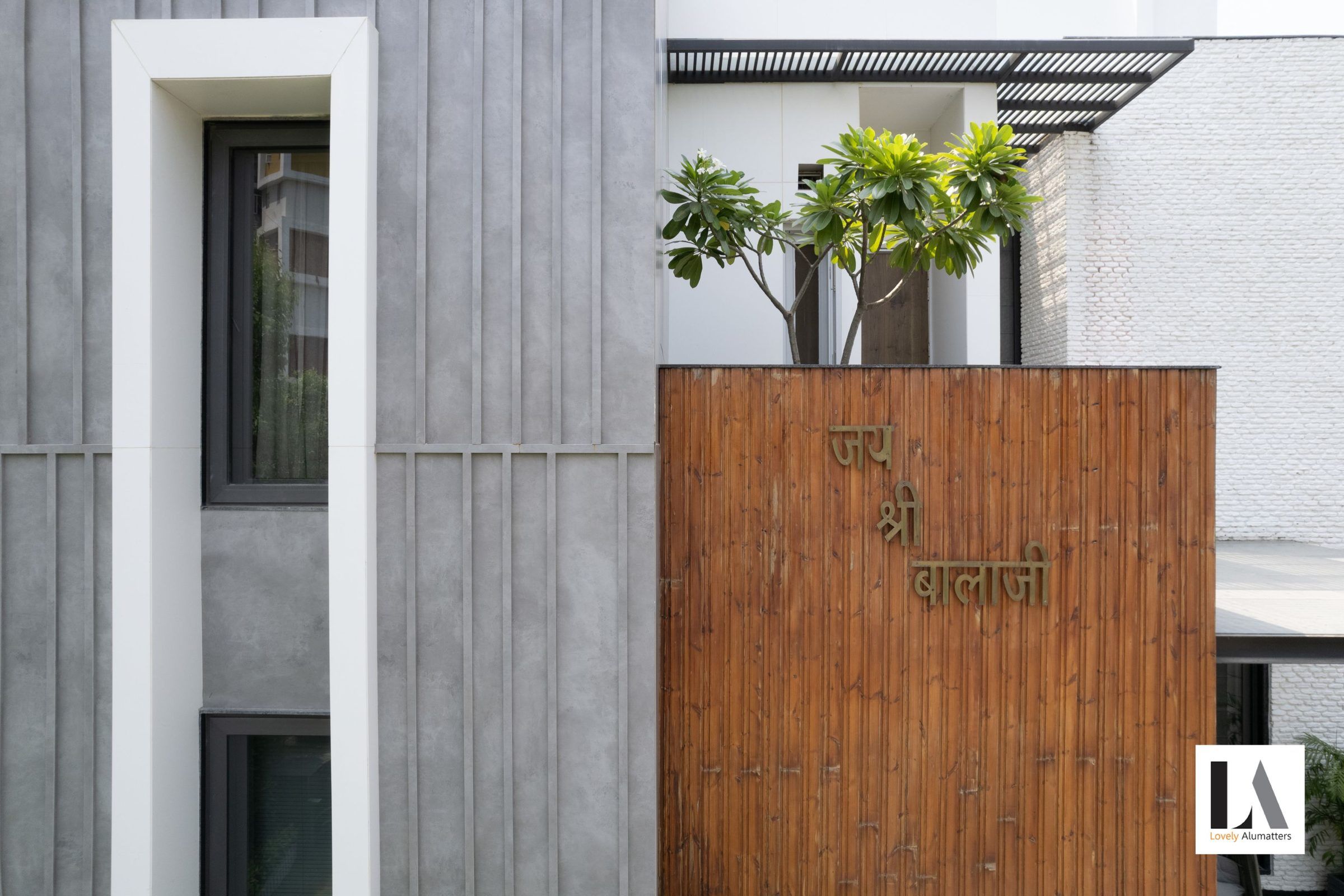 Concrete façade with a tall narrow window beside a timber-clad entrance