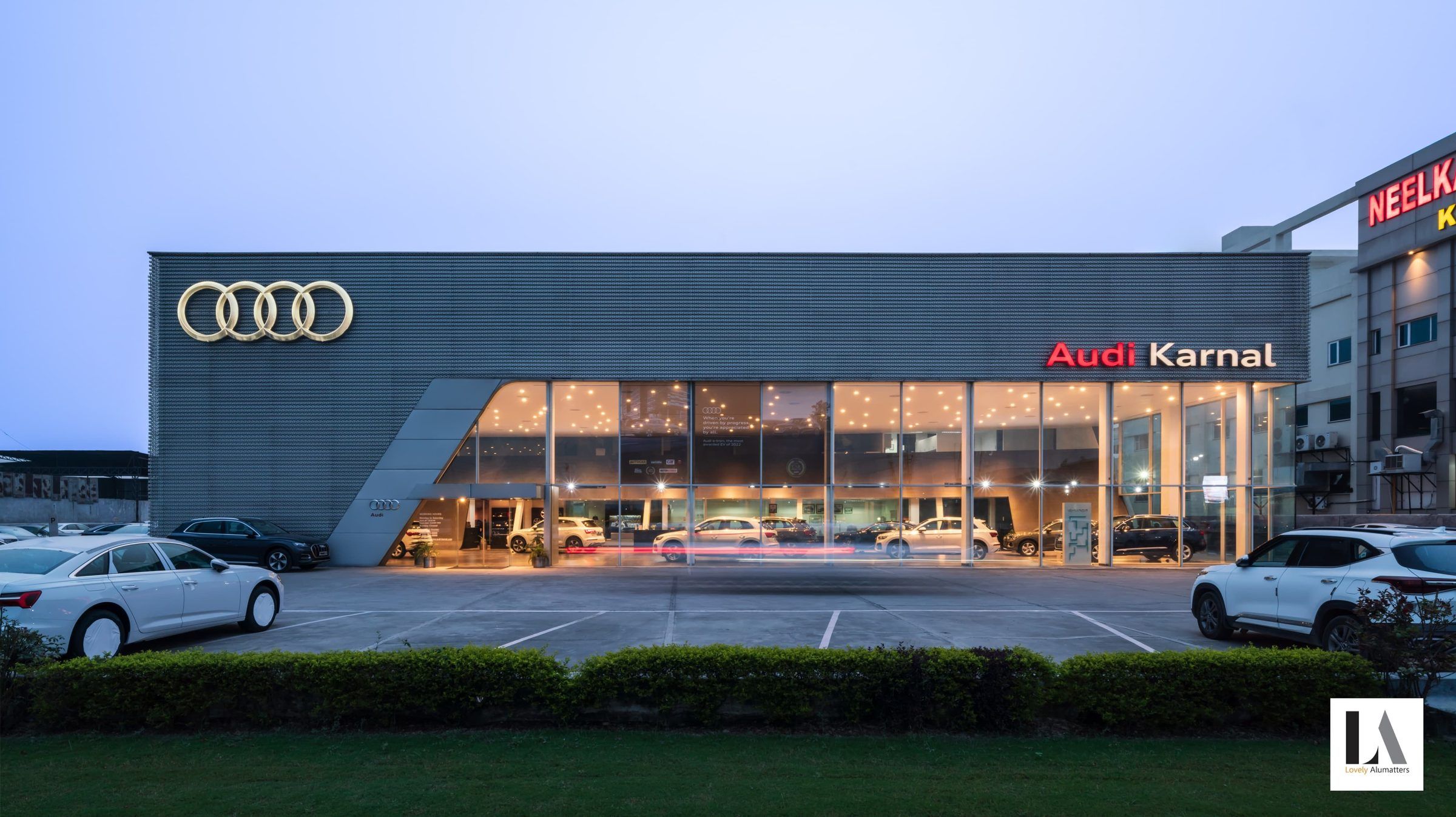 Automotive showroom at dusk with a long illuminated glass frontage