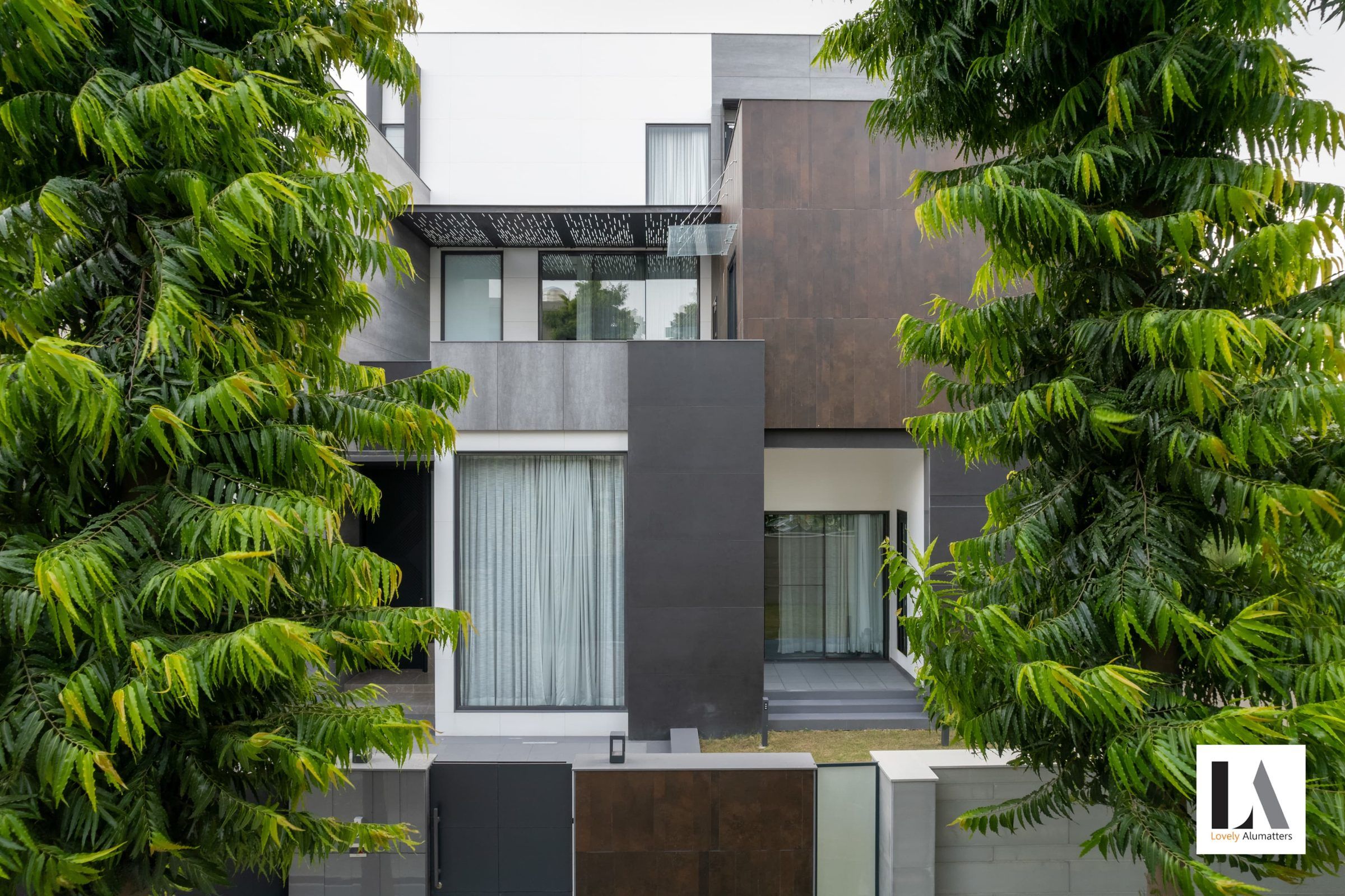 Residence framed by trees, with large windows across white and dark volumes